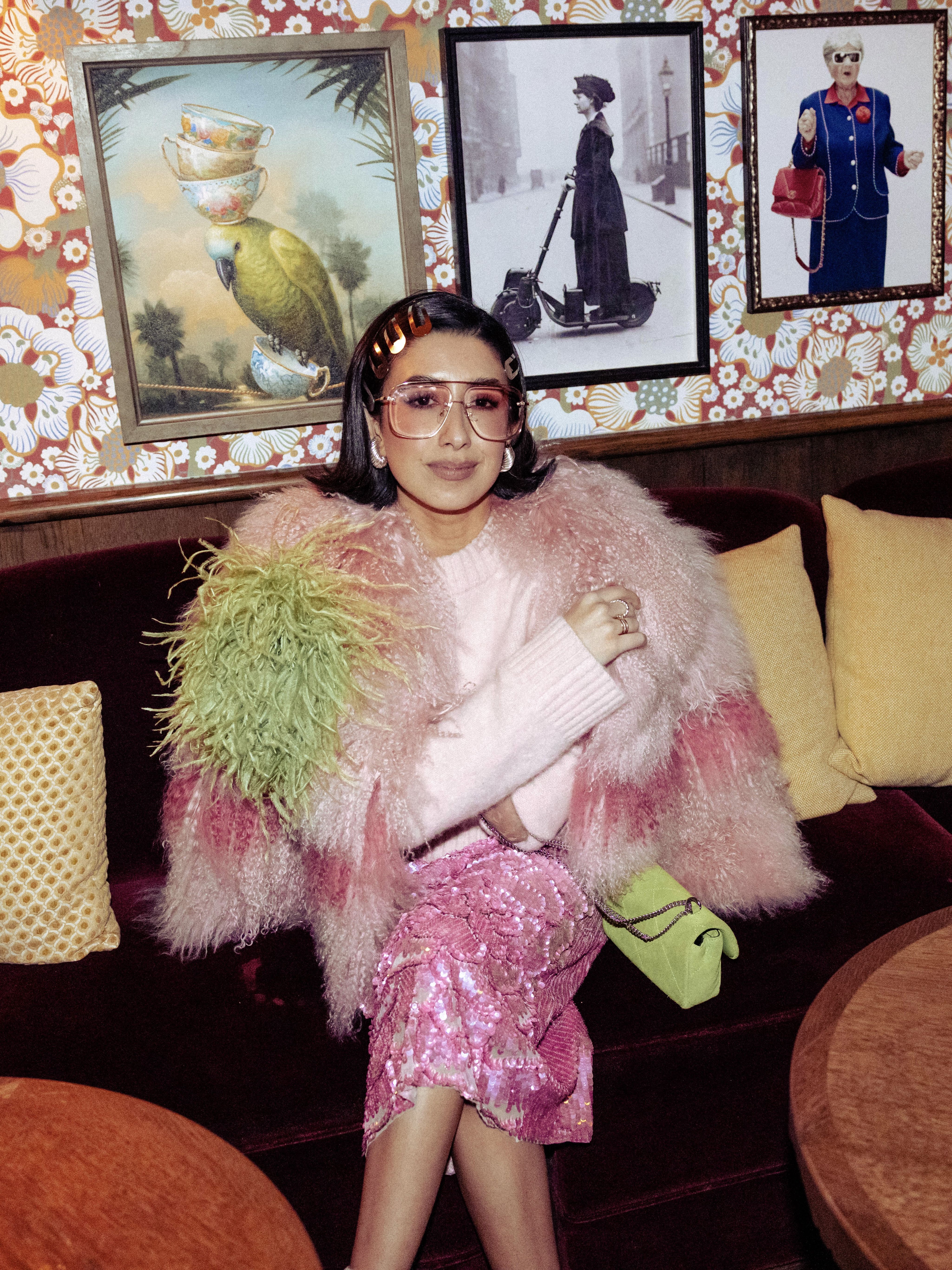 April Lockhart accessorizes a maximalist pink look with a lime green bag and feather brooch