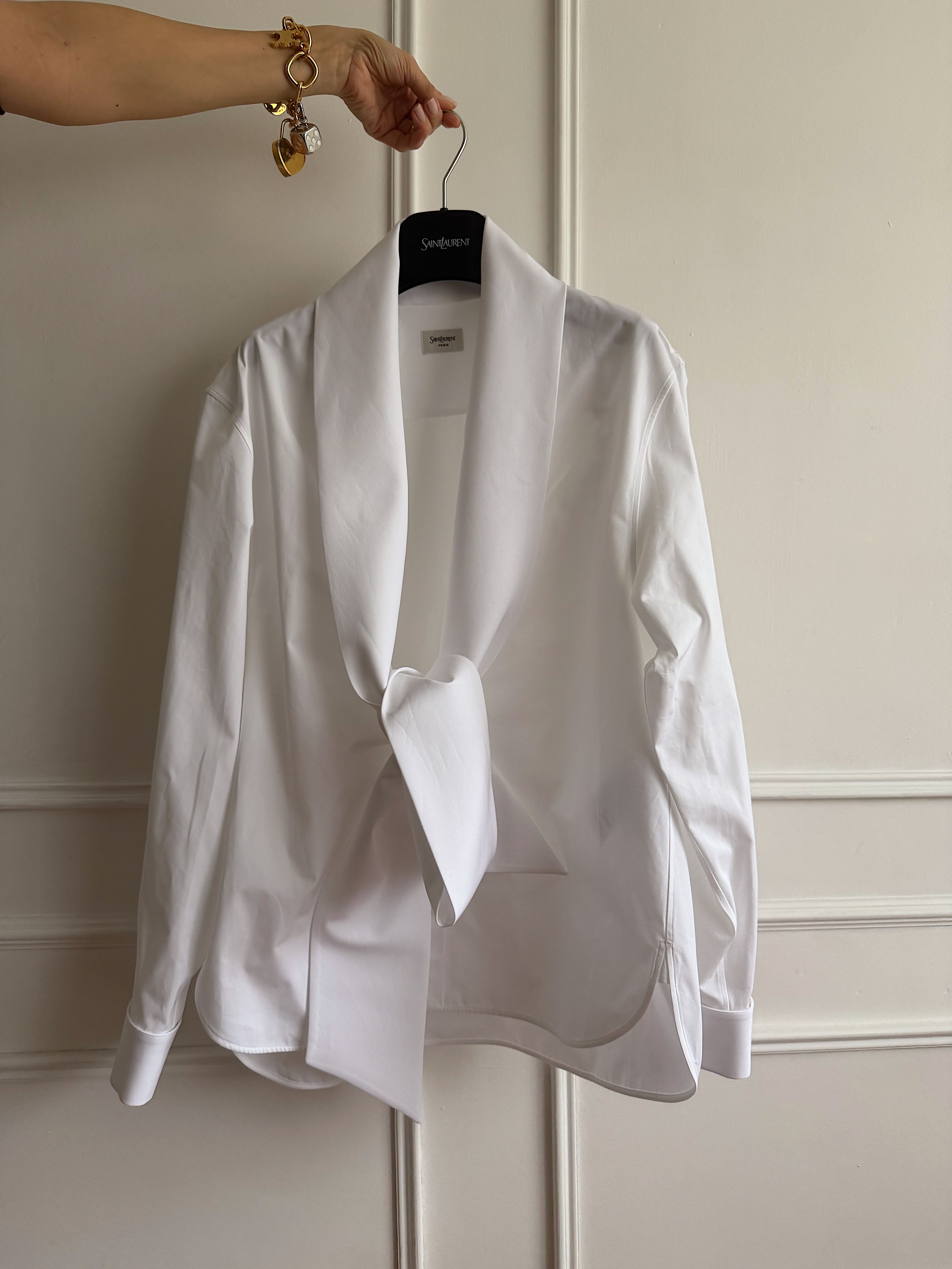 Renia Jazdzyk holds out her Saint Laurent shirt with a charm-adorned hand