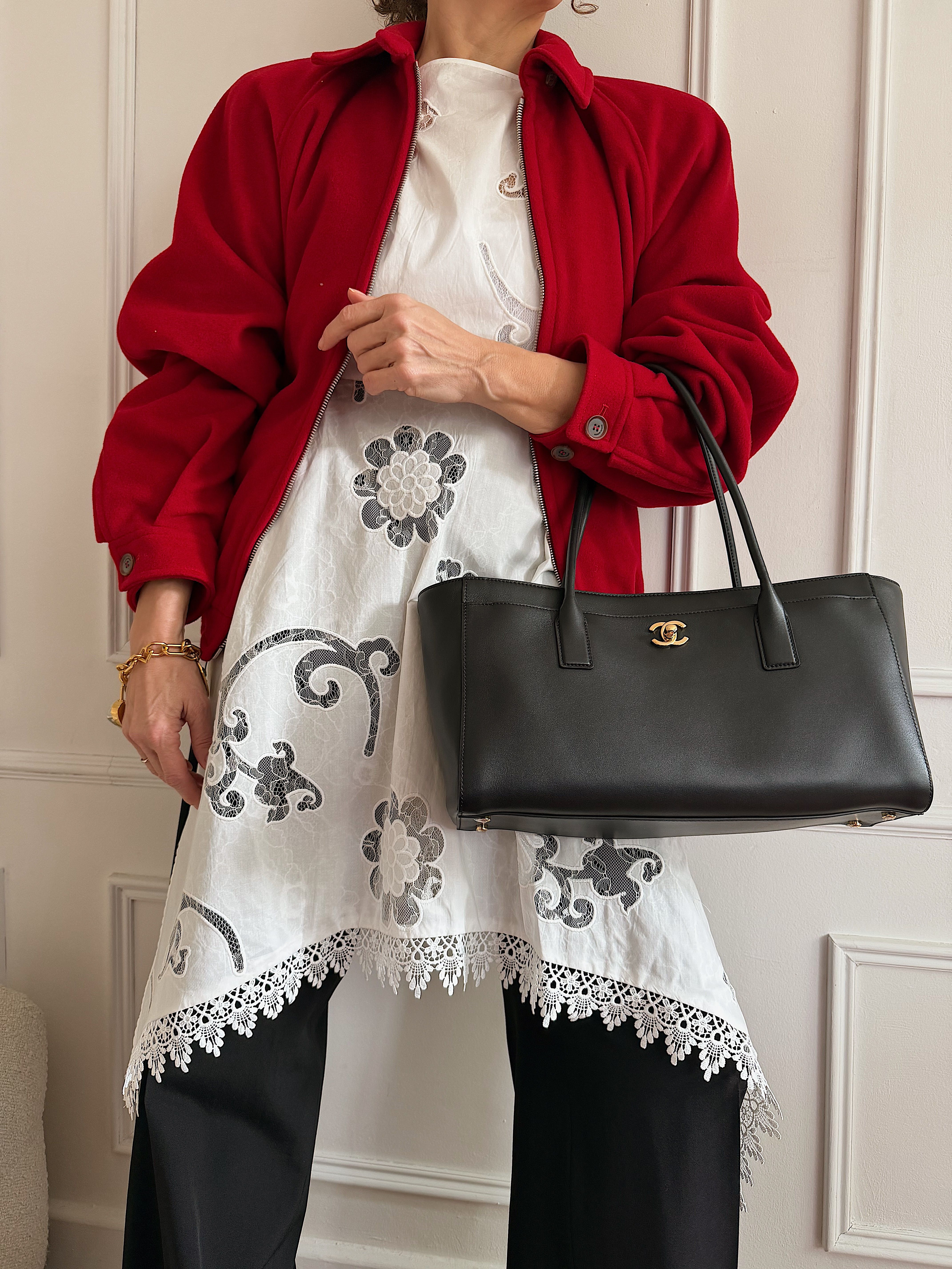 Renia Jazdzyk wears a red jacket over a dress and pants, with a black leather Chanel bag