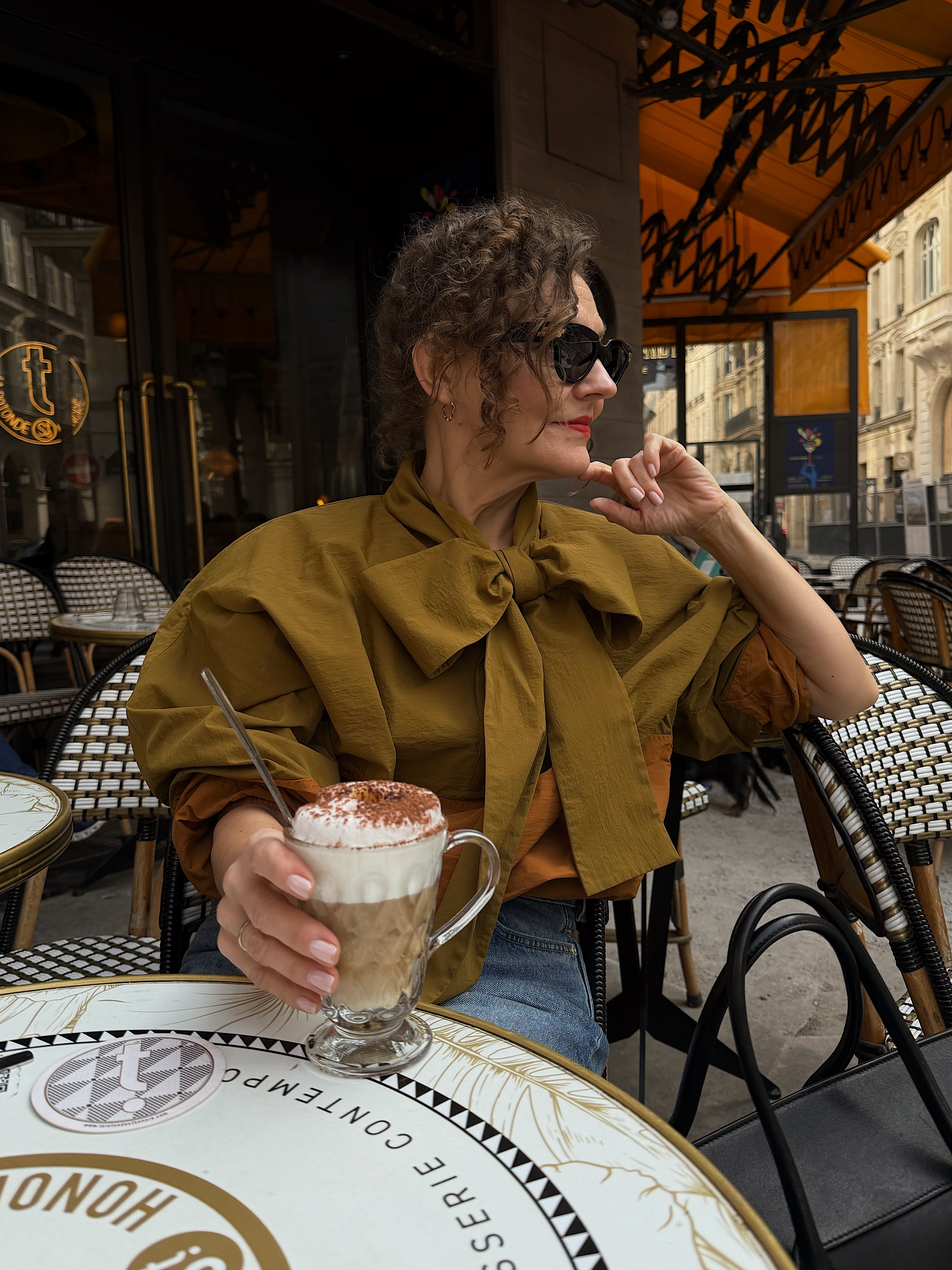 Renia Jazdzyk styles a bow-embellished windbreaker with jeans and sunglasses