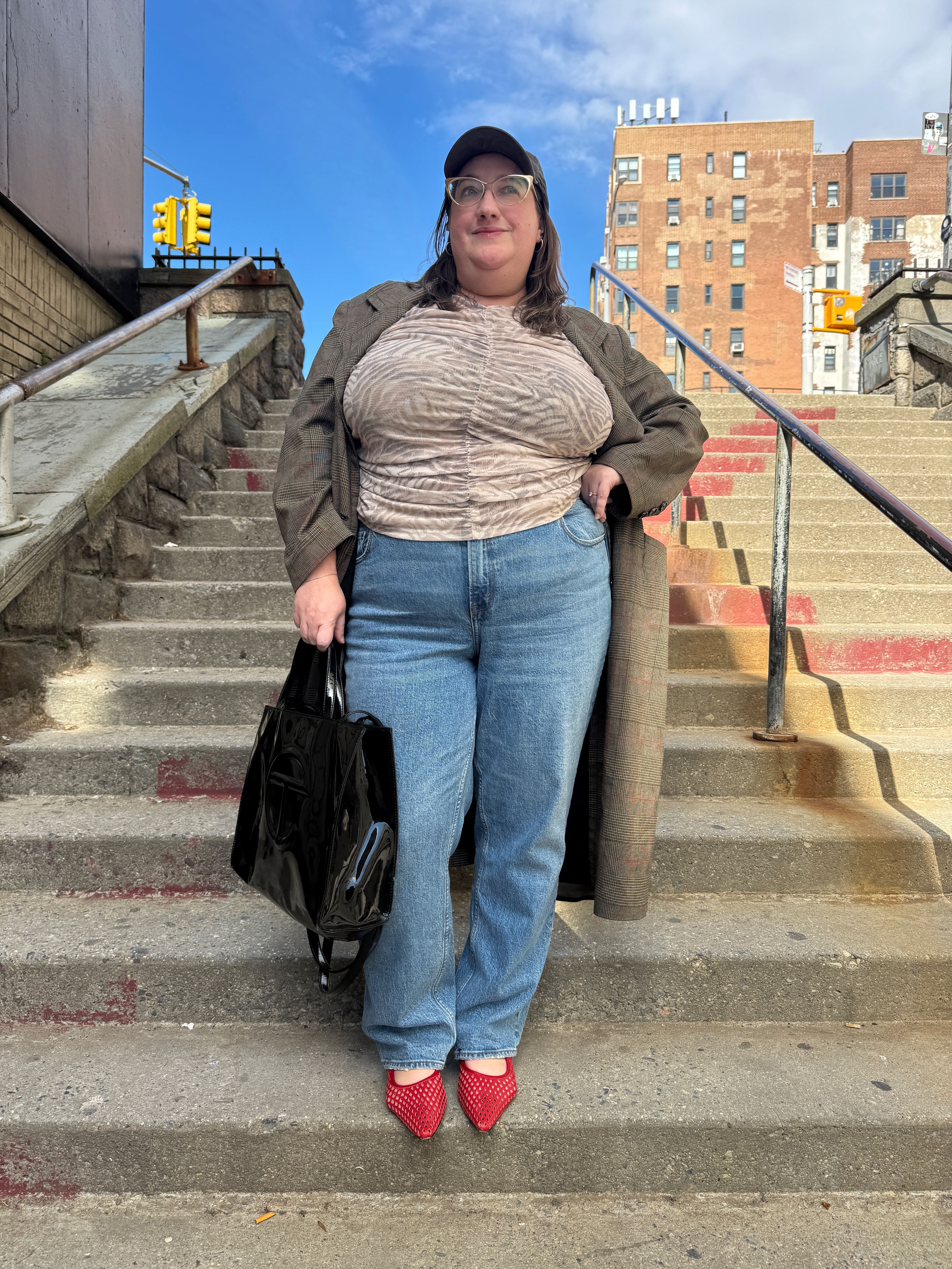 Sarah Chiwaya wears a lightweight longline jacket over straight-leg jeans and red mesh flats