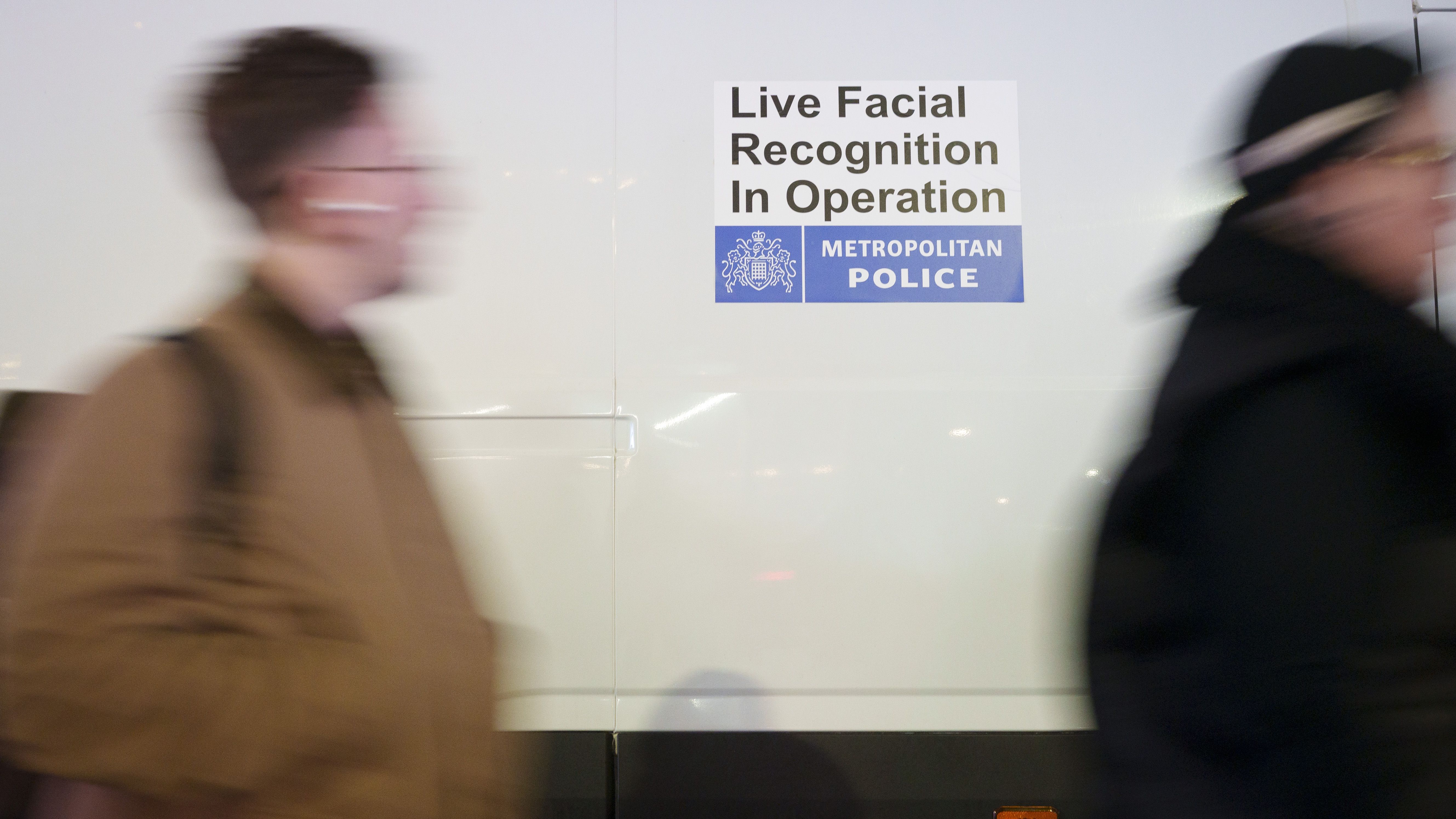 an image of shoppers walking past a Met police van that's using Artificial Intelligence (AI) Facial Recognition (FI) technology to spot persons of interest at Tottenham Court Road