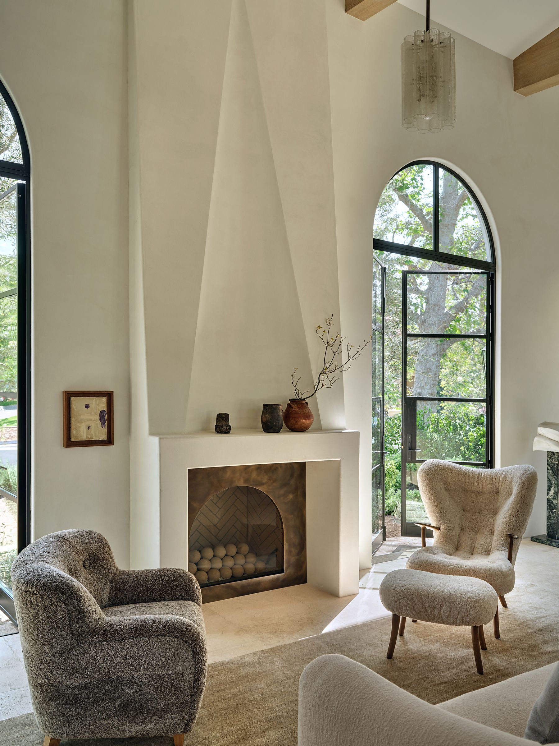 white living room with large white fireplace and. modern boucle armchairs