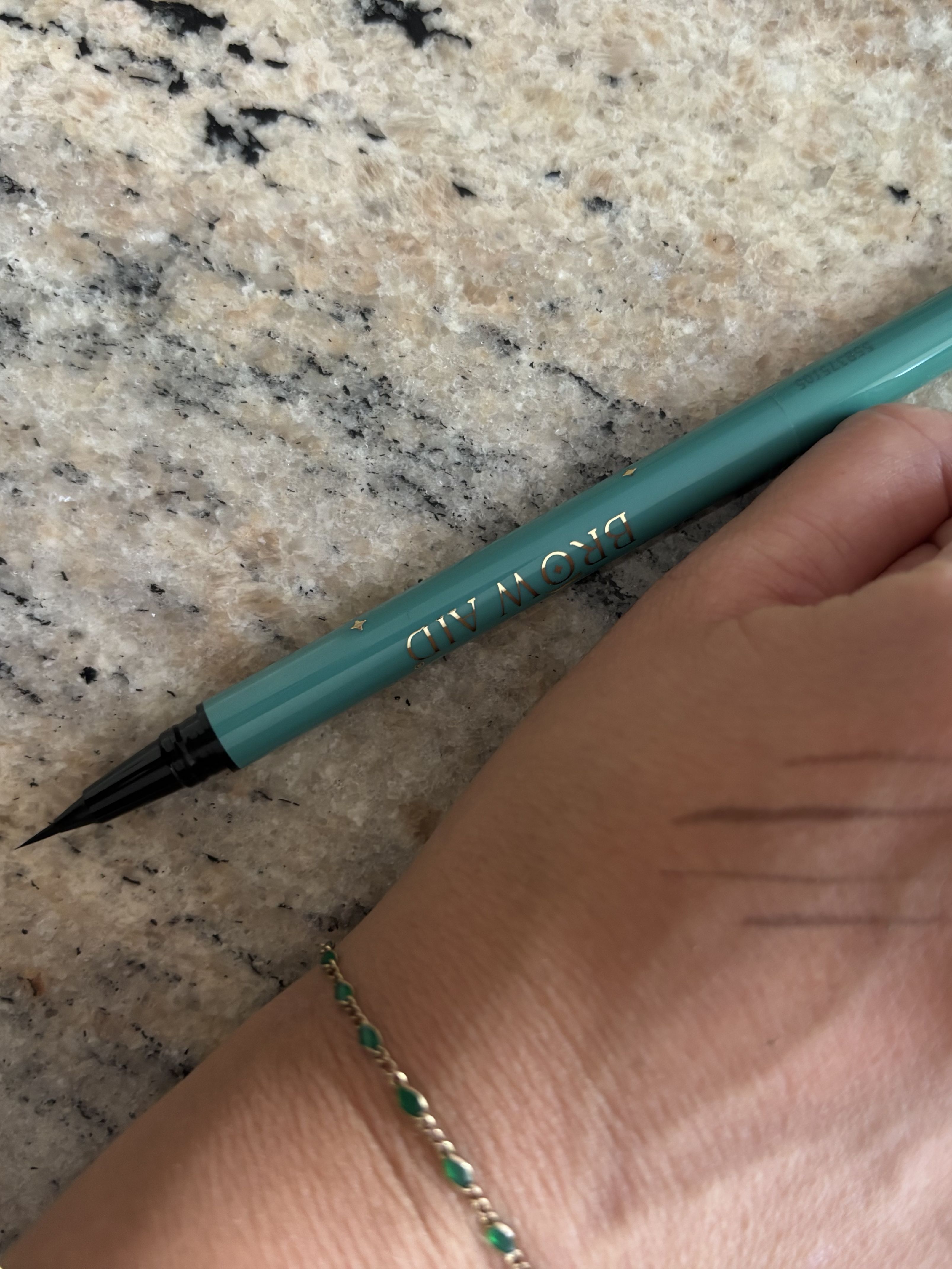 Beauty editor Perdita swatching the Brow Aid Masterstroke Brow Trio on her hand