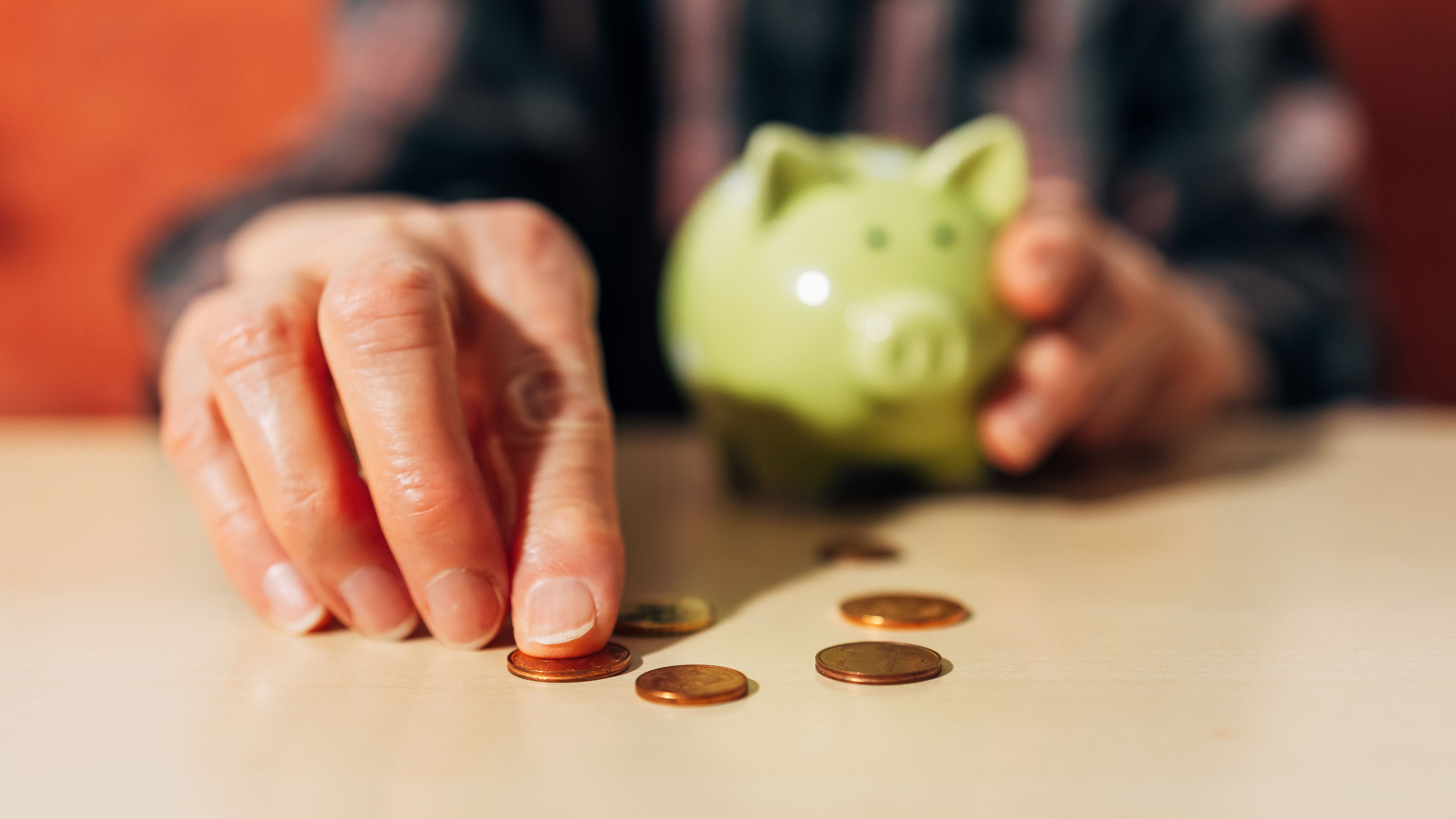 A close up of a senior man's hands as he counts pennies from his piggy bank.