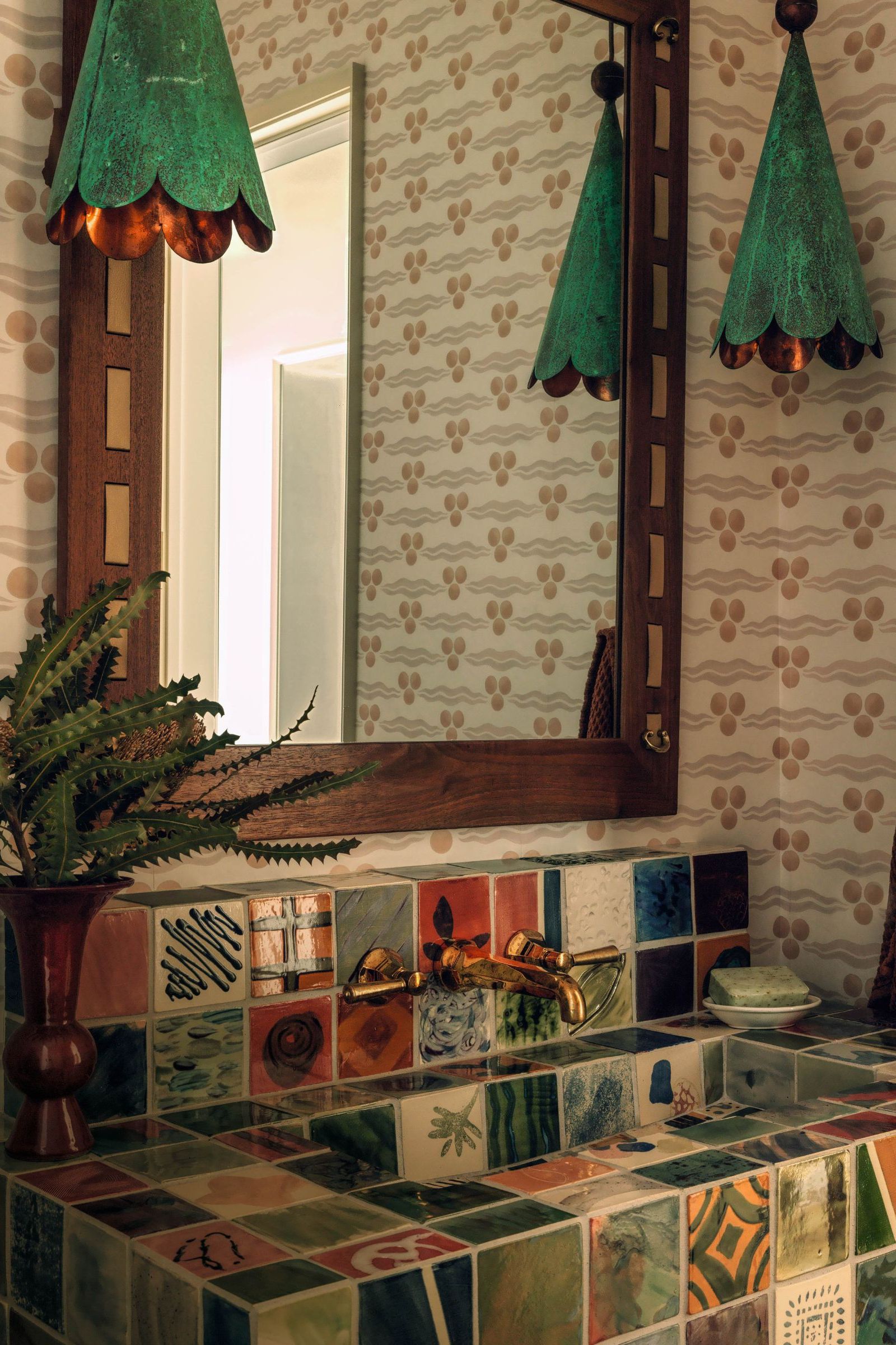 Powder room with statement tiled sink, wooden mirror, green pendant lights and patterned wallpaper