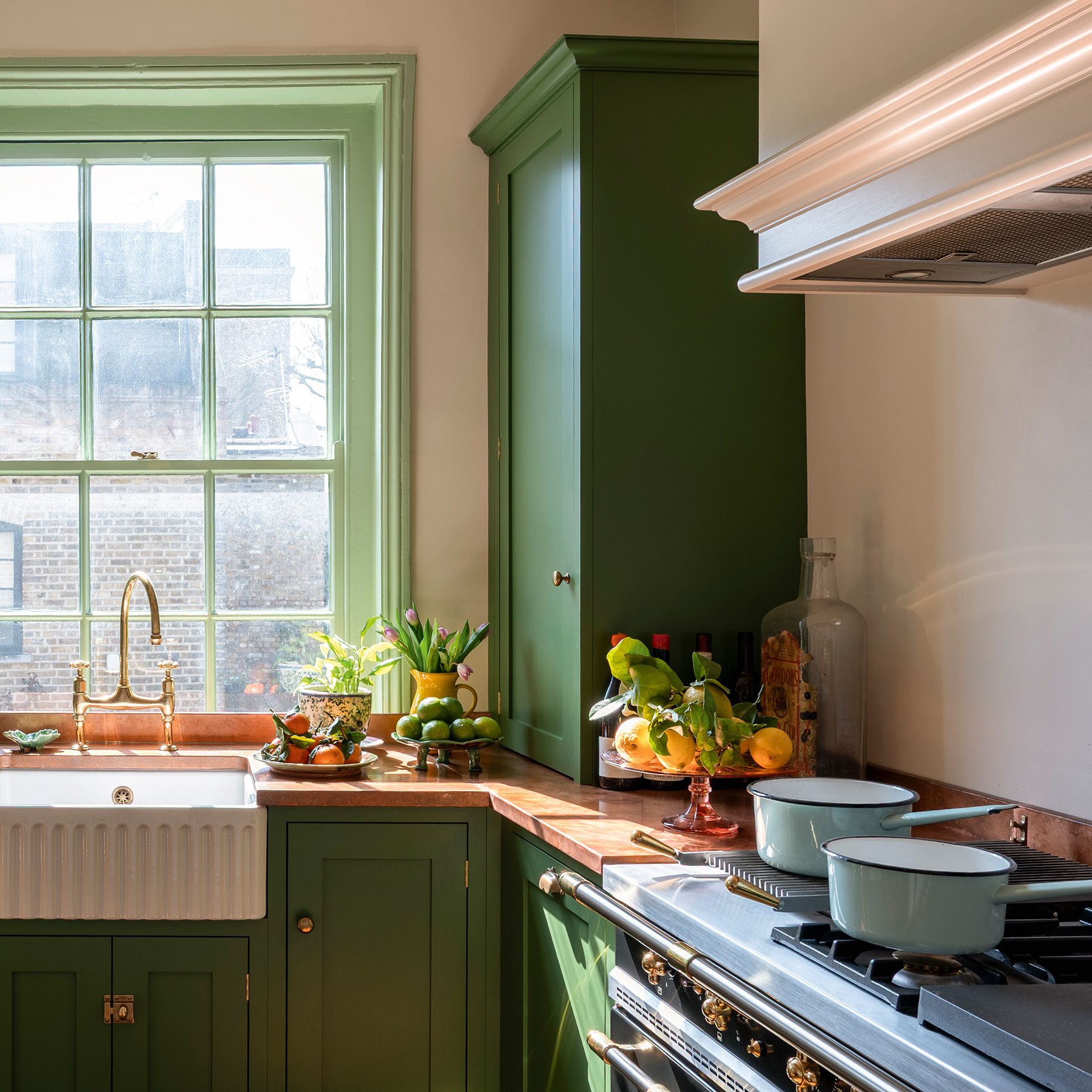traditional kitchen with green cabinetry and woodwork, cream walls and wooden floors in a 17th-century london maisonette