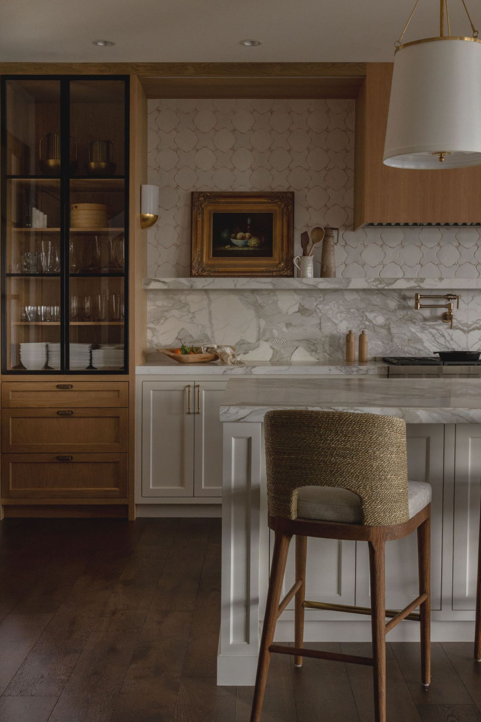 A warm kitchen with wooden cabinets, a marble countersplash which ends in a shelf, and a tiled wall to extend the backsplash to the ceiling