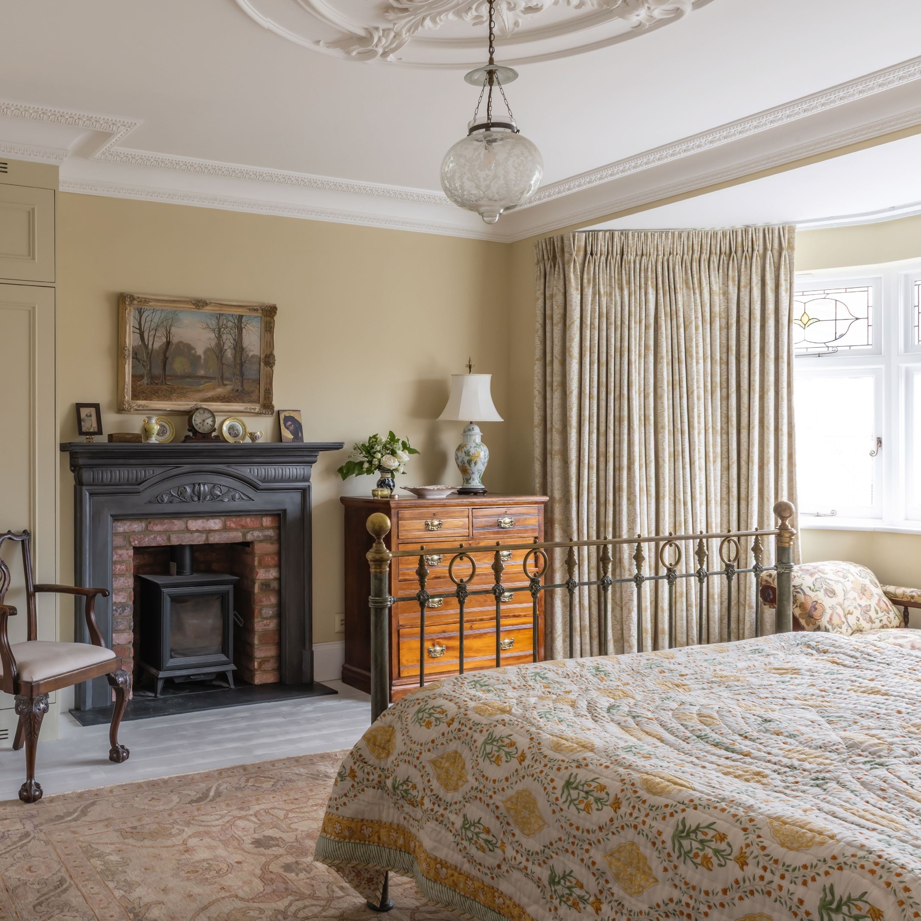 Traditional style bedroom with fireplace, antique furniture and bay window