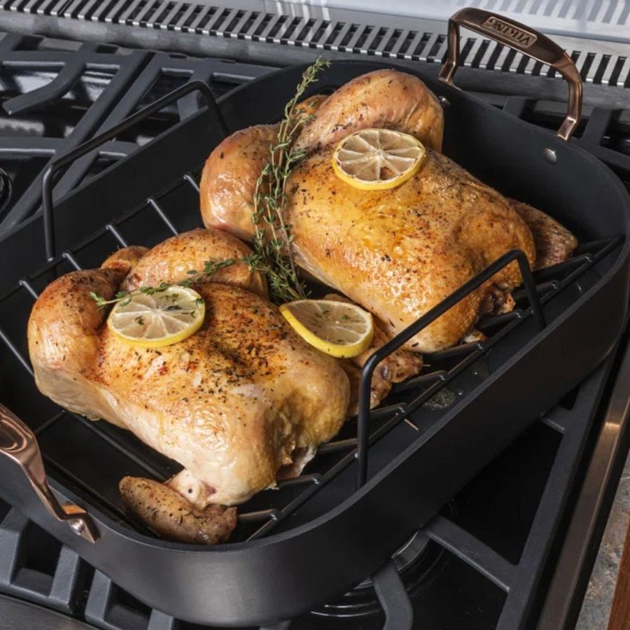 Turkeys in roasting pan on stovetop, next to wooden board and carving knives