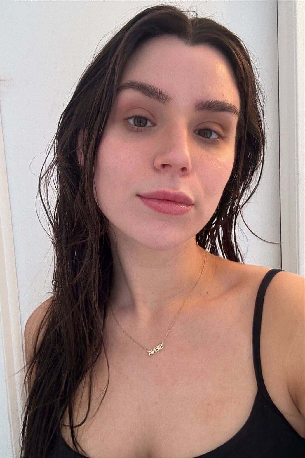 A girl with long brown wet hair, a black tank top, and dark brown eyes.