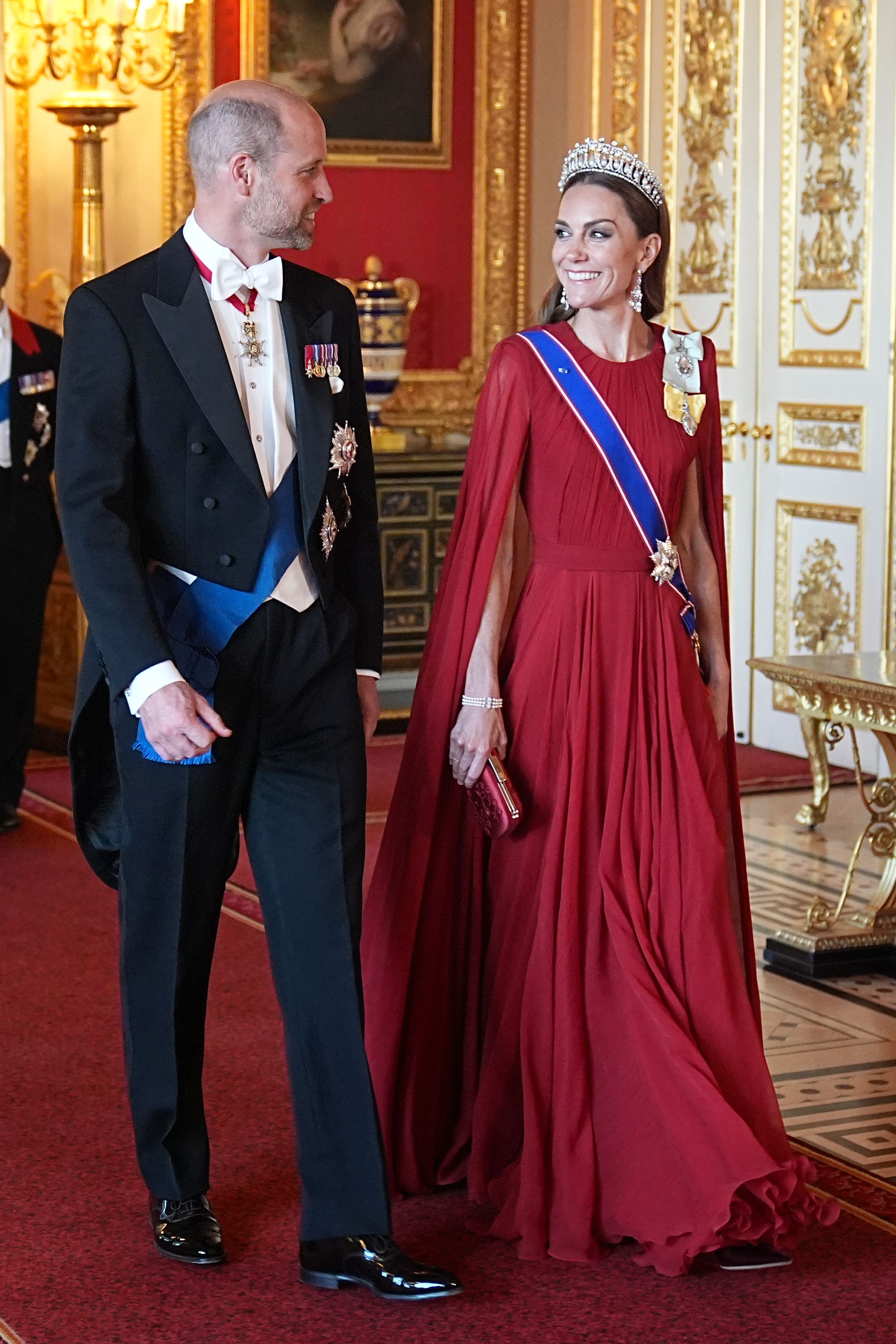 Princess Kate in a red gown and tiara walking with Prince William, with Princess Anne, Prince Edward and Duchess Sophie behind them at Windsor Castle