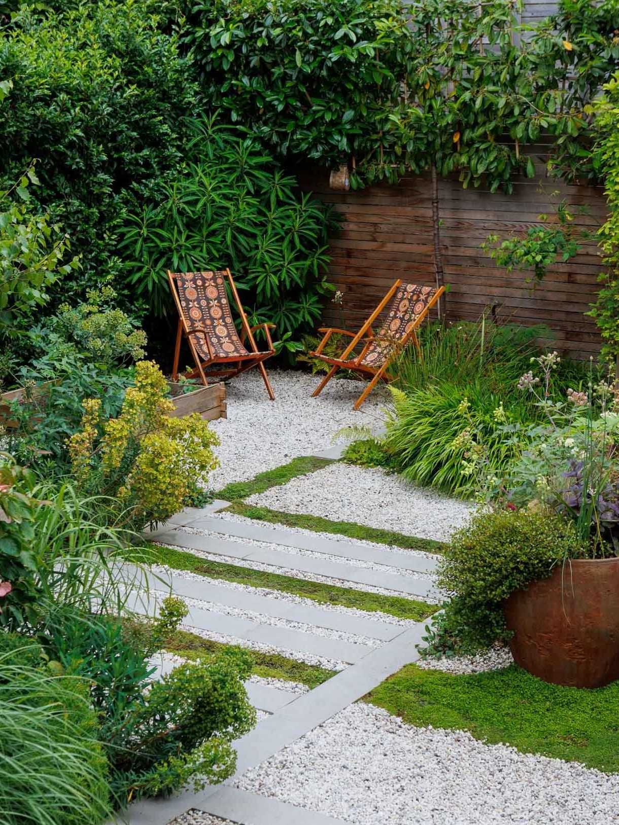 garden corner with deck chairs, lush planting, gravel, pavers and ground cover