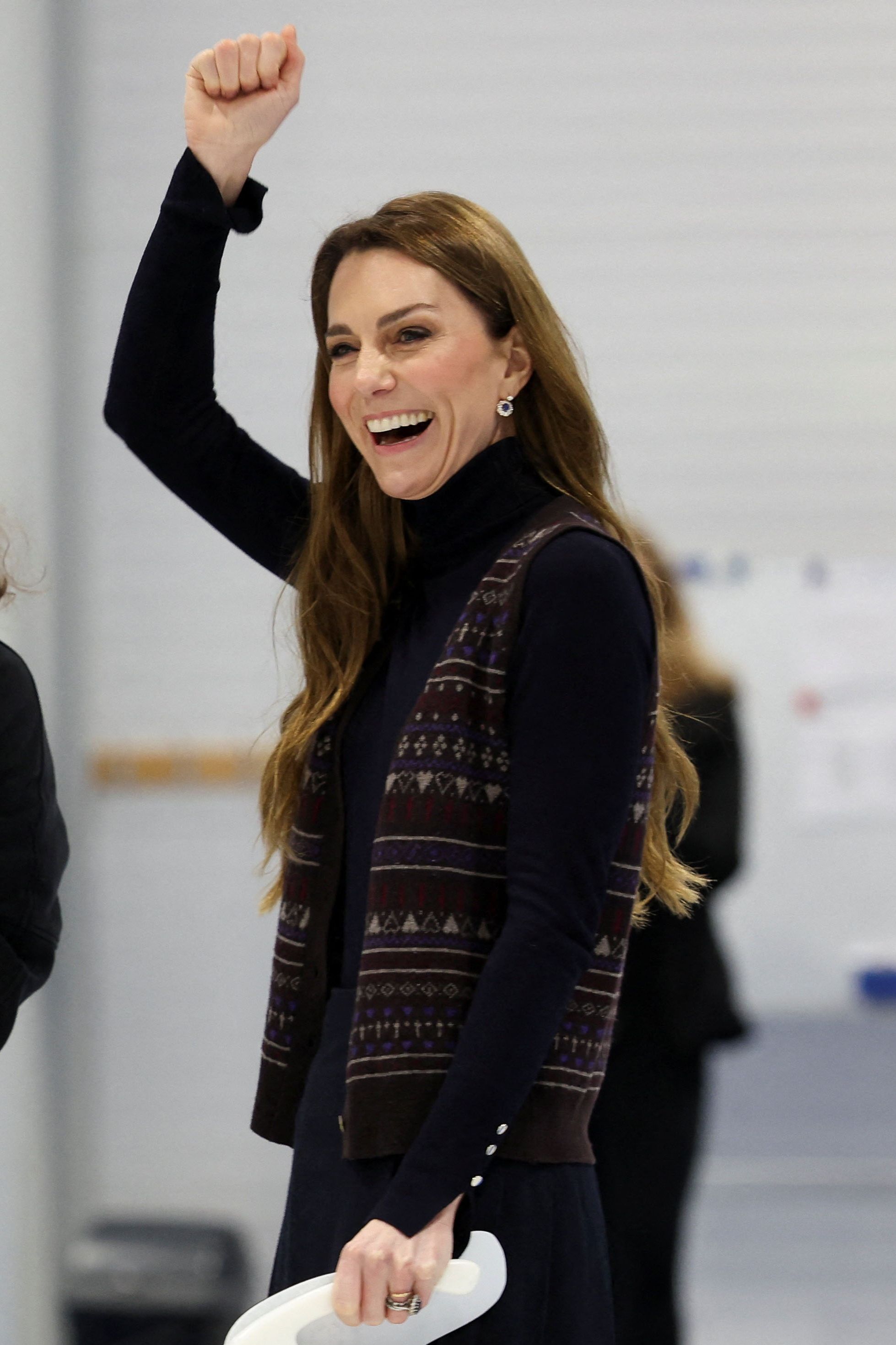 Britain's Kate, Princess of Wales reacts next to Scottish curler Jen Dodds while participating in curling