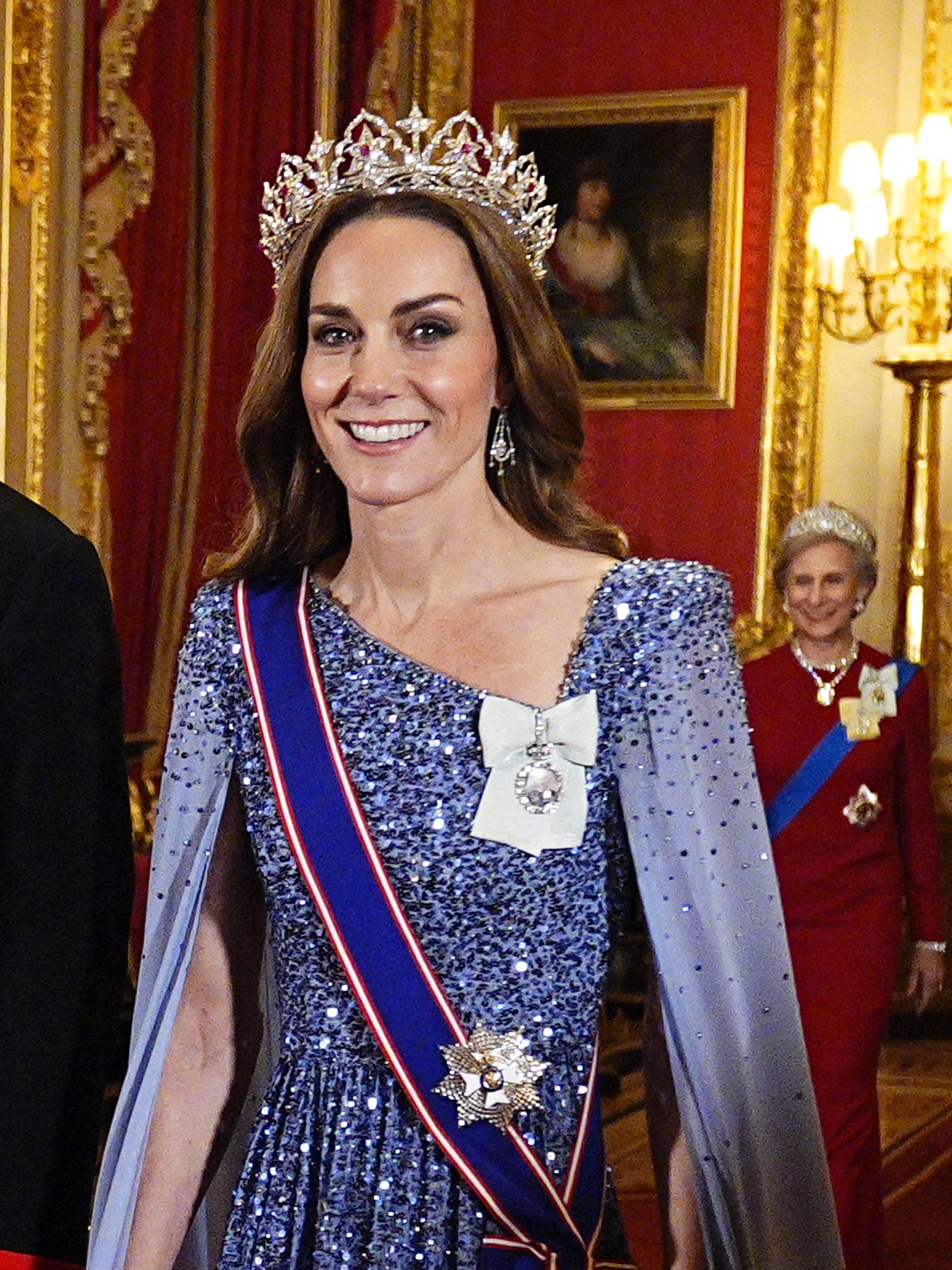Kate Middleton wearing a blue gown and a tiara walking next to Prince William