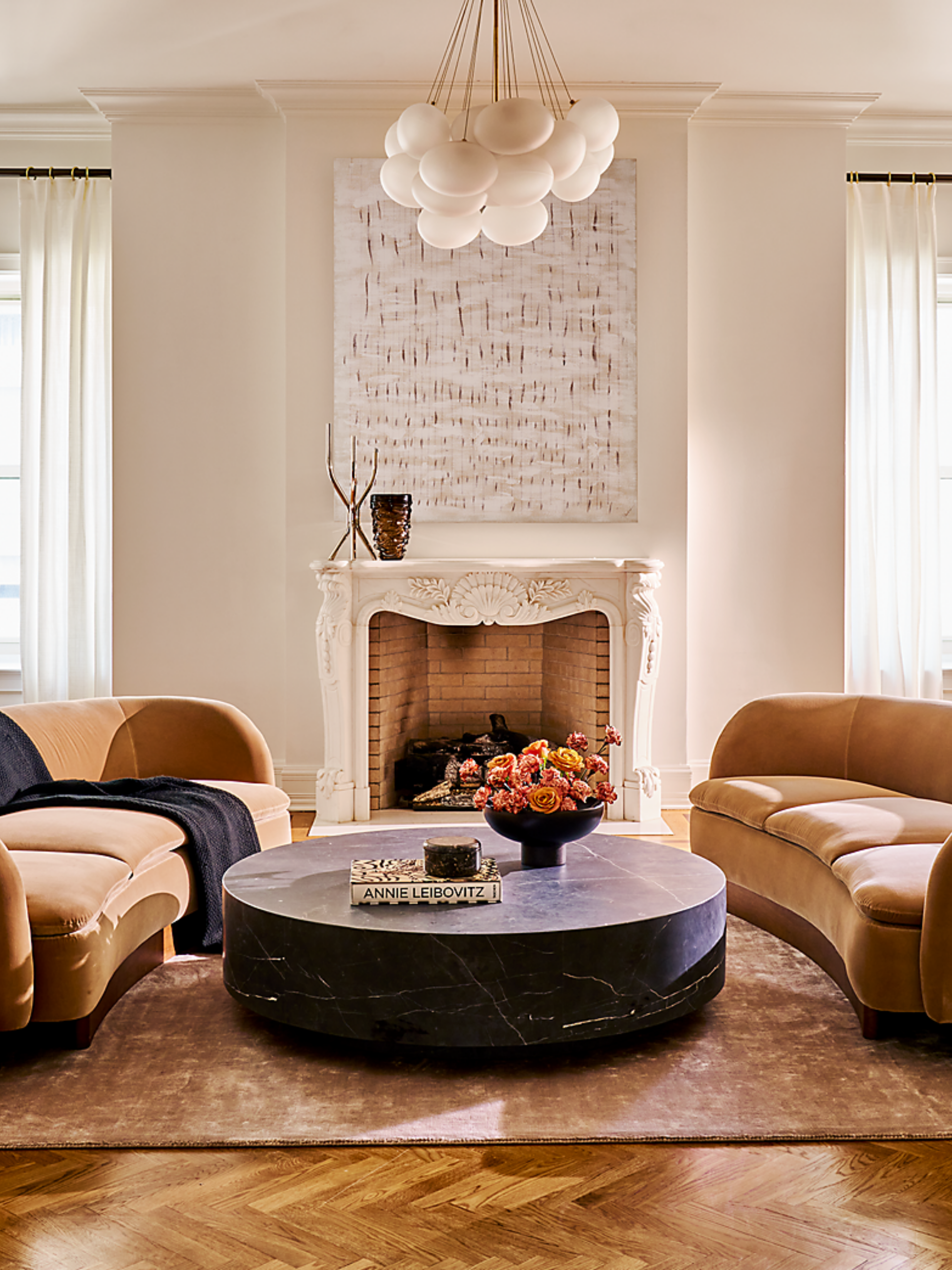 Neutral traditional living room with antique molding, herringbone wood floors, and two contemporary camel velvet curved couches