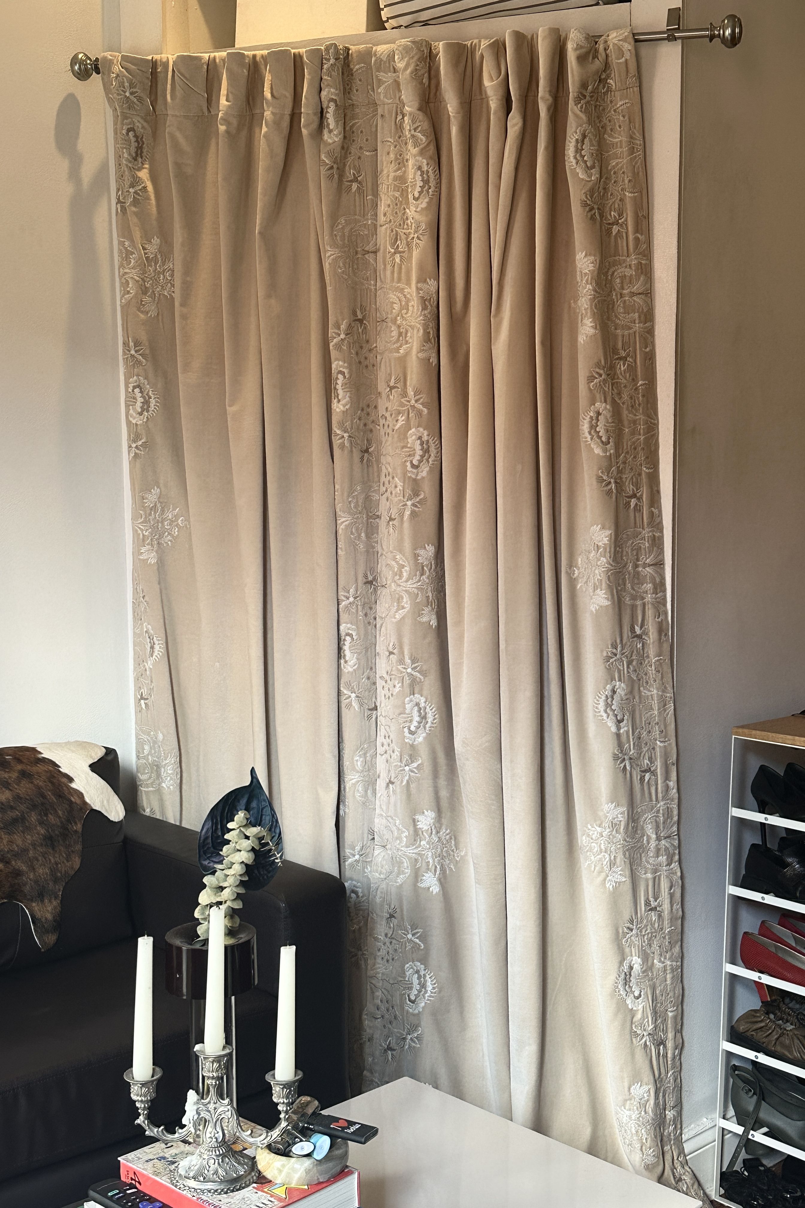 Anthropologie Harlowe Curtains hanging in an NYC living room with assorted vintage objects, including a cowhide an silver candelabra.