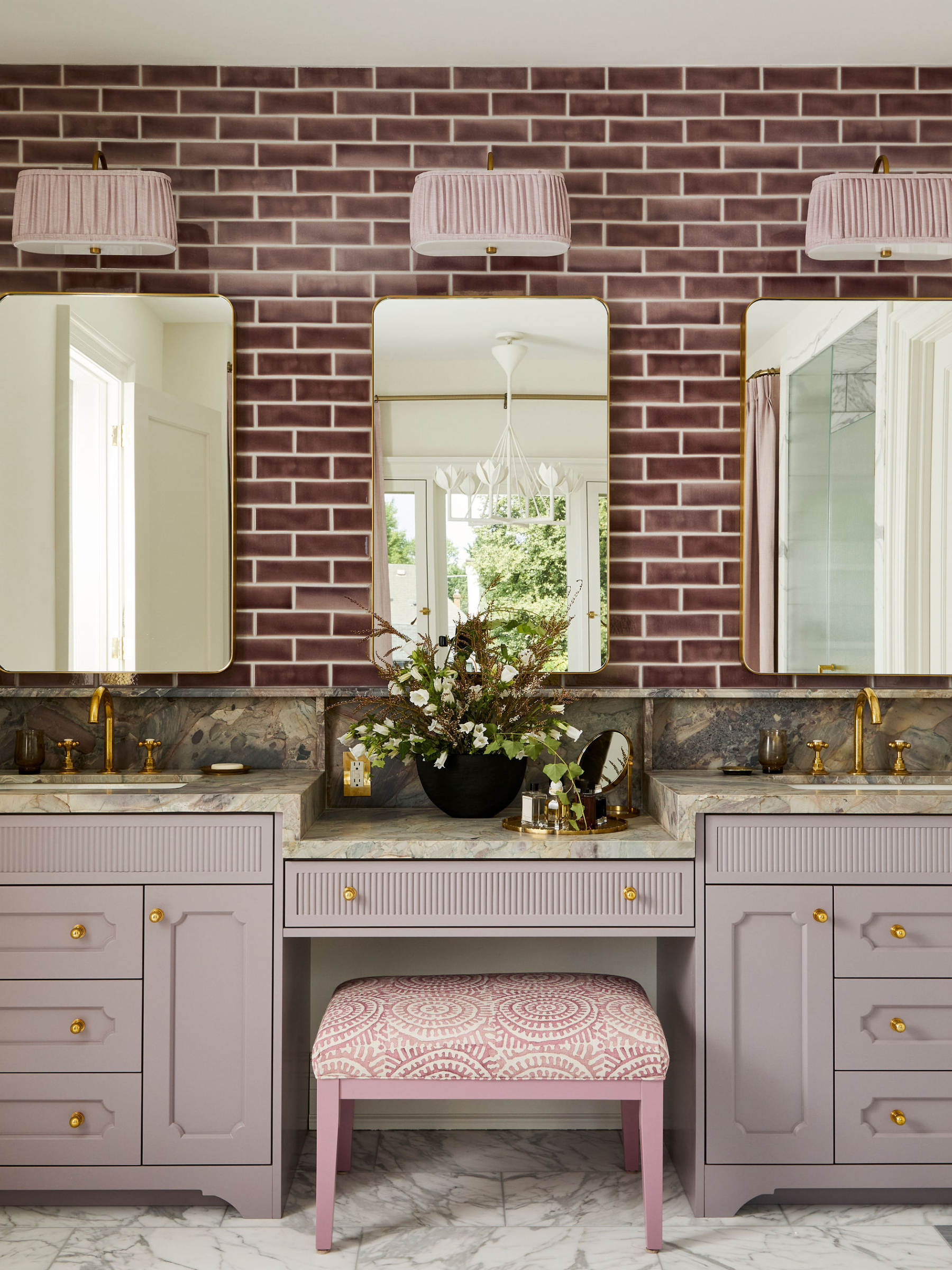 A split image of a primary bathroom with pink-toned curtains behind a floating tub, and a vanity area with three medicine cabinets backed by berry-colored rectangular tiles.