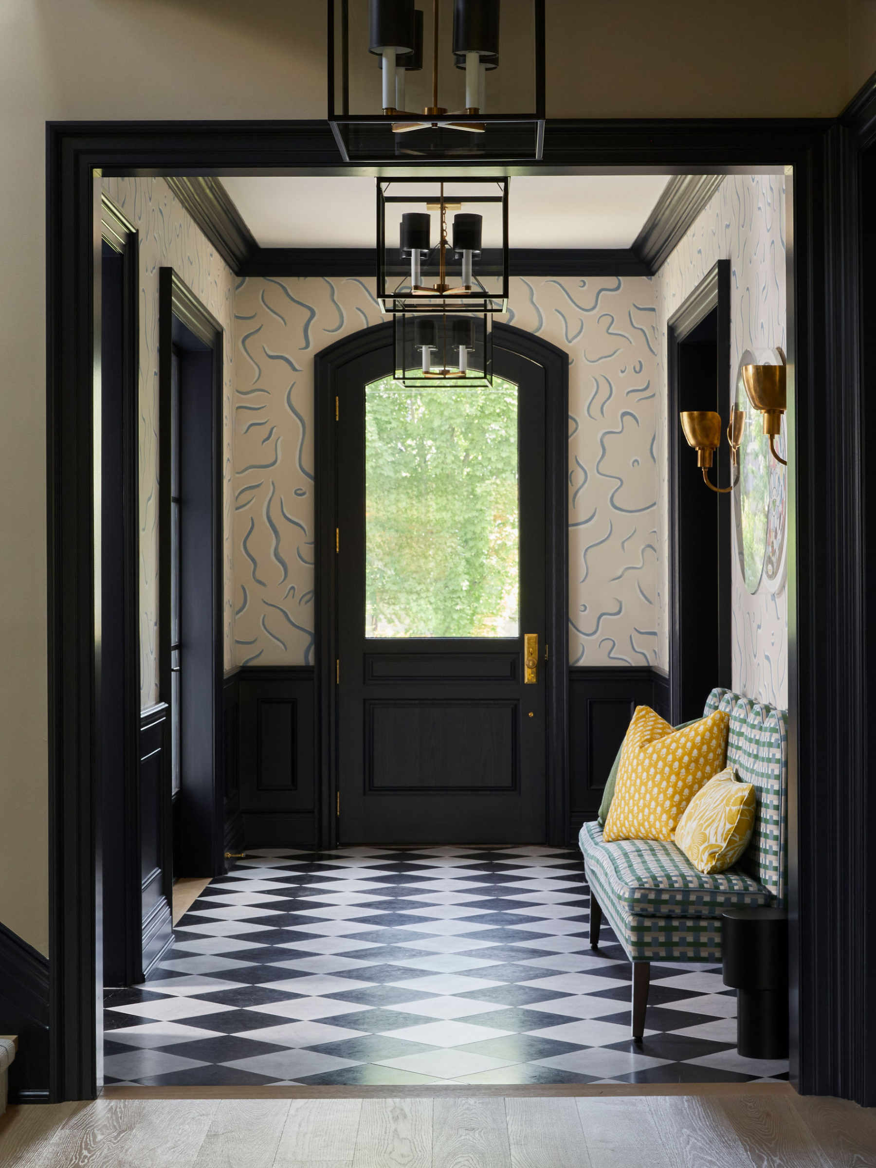 A split image of a foyer in a Toronto home with expressive wallpaper surrounded by black moulding and wainscoting.