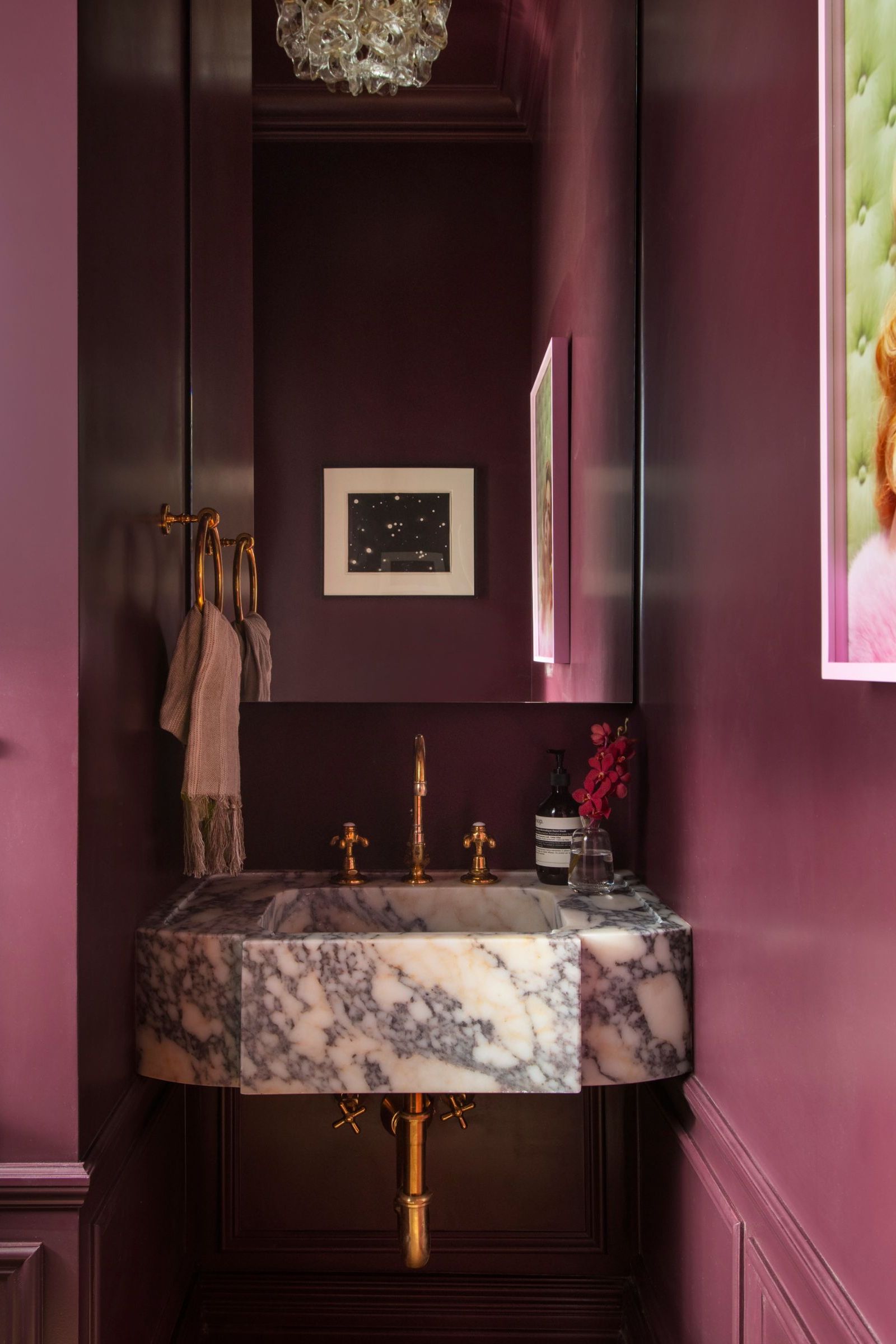 Aubergine painted bathroom with marble sink, long mirror and gold tap and light switch