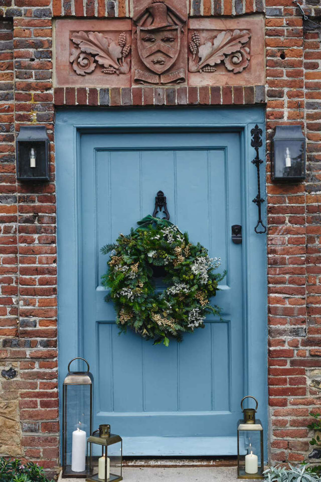 a brick house with a blue front door with a wreath hanging from it