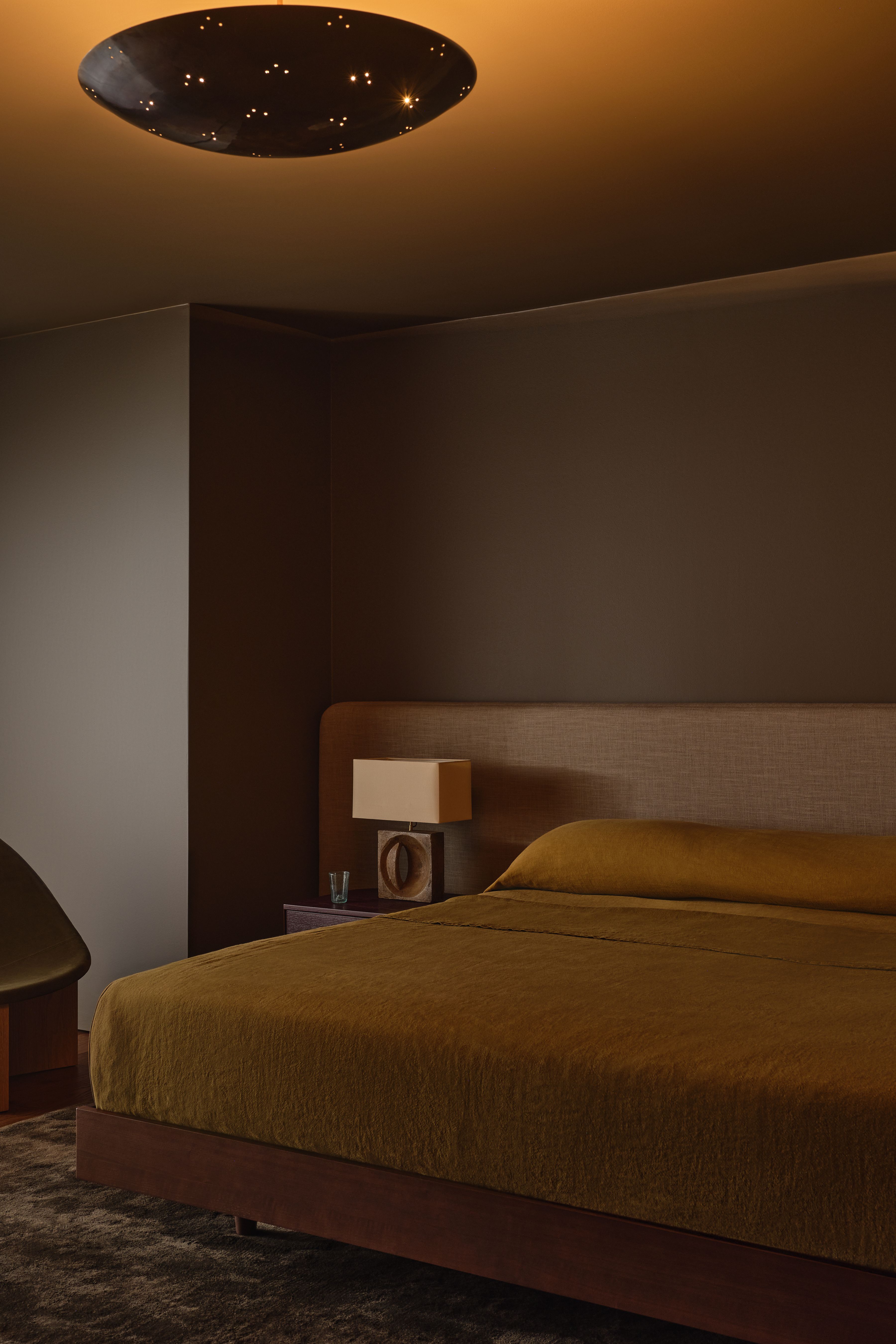 Serene bedroom with minimalist flush mount glowing softly overhead.