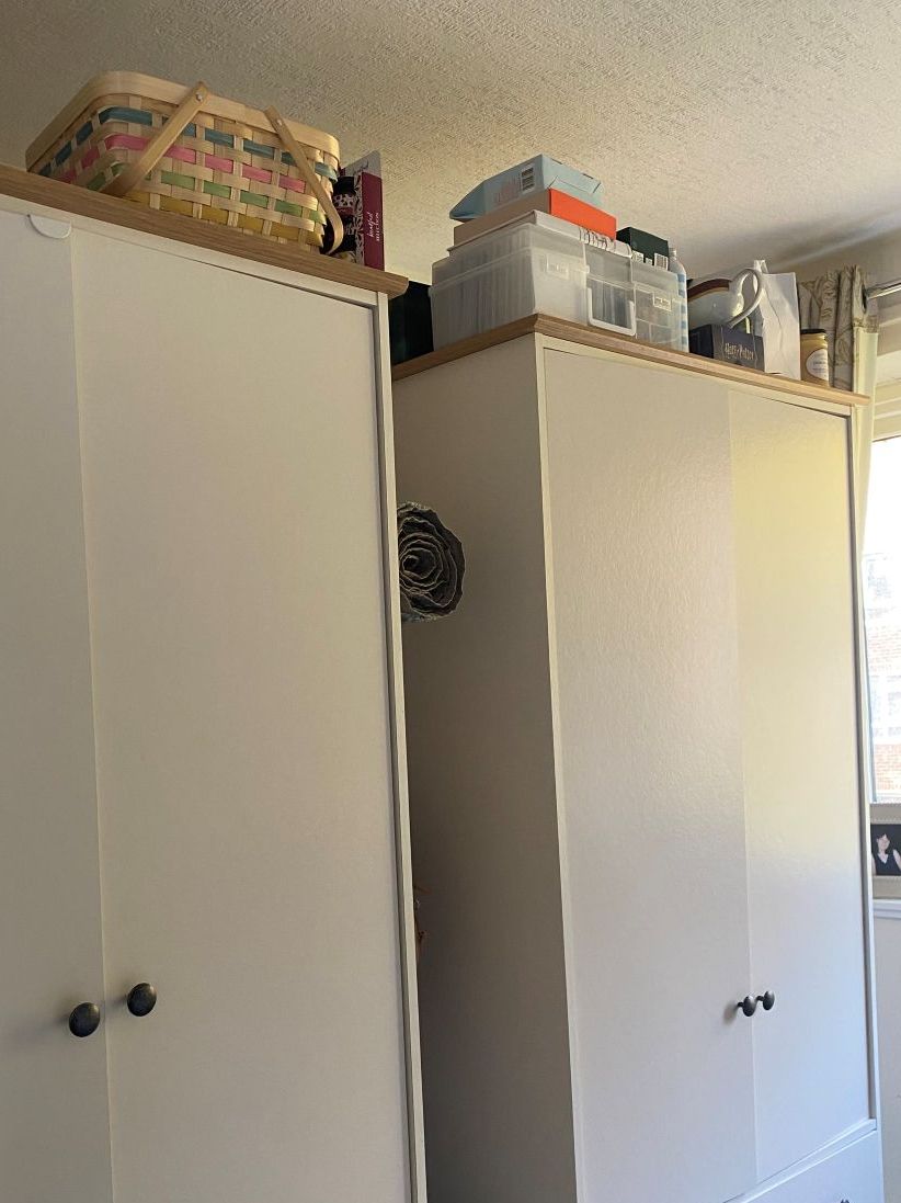 two white wardrobes with items stored on top