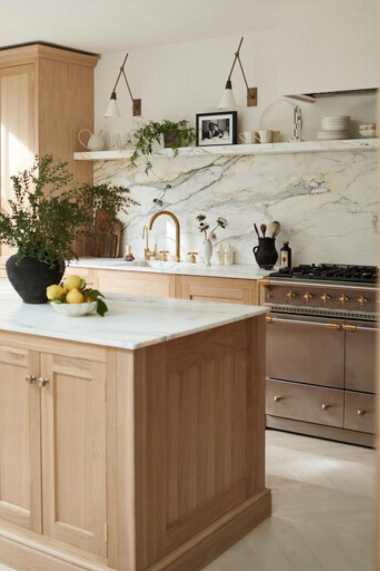A light wood sociable kitchen with marble countertops, a large island, and counter seating