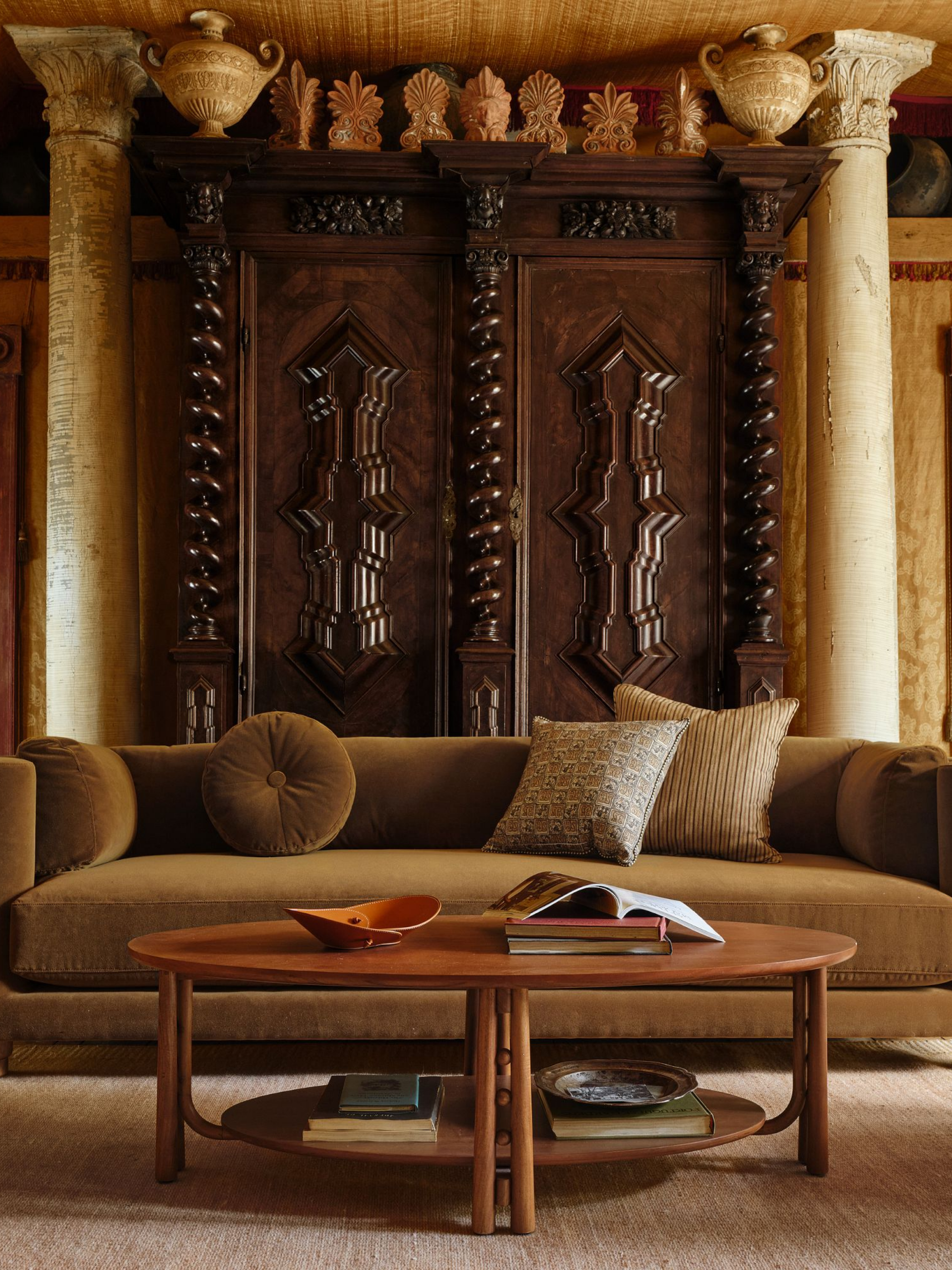 Rolled arm sofa in moss green by Pierce &amp;amp; Ward for West Elm, pictured in a Tudor-style living room with elaborate wood paneling and twin marble posts.