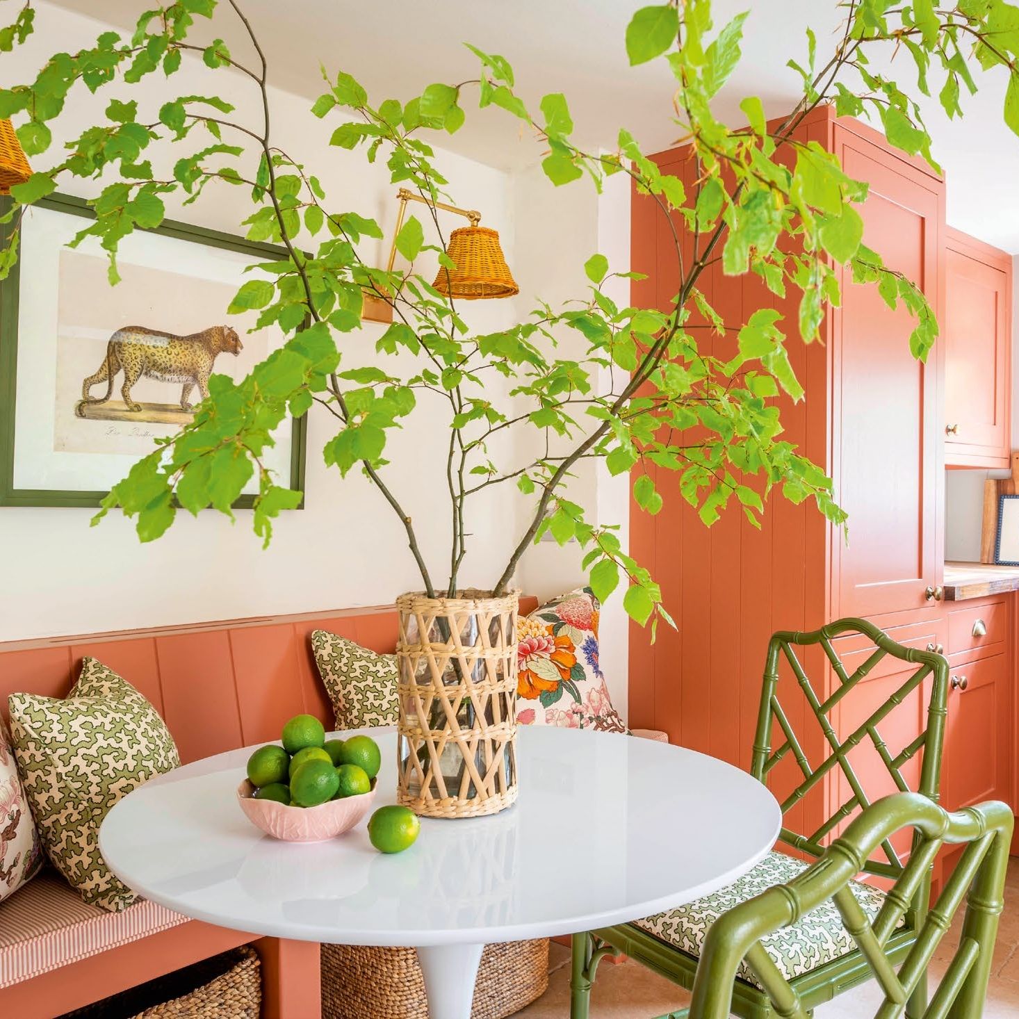 Cream room with pink cupboards and bench, white table and green chairs