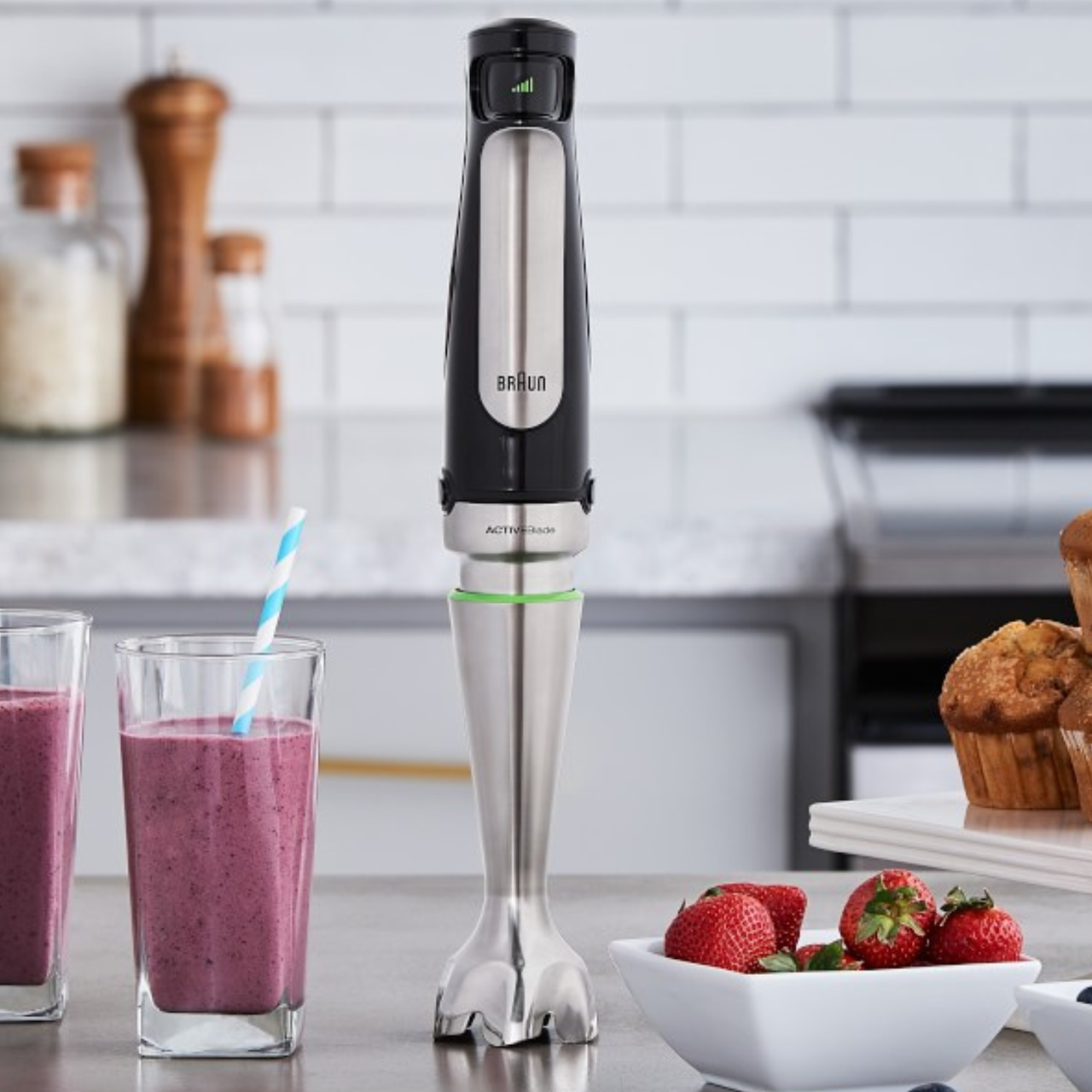 Braun immersion hand blender on a countertop next to smoothies and muffins