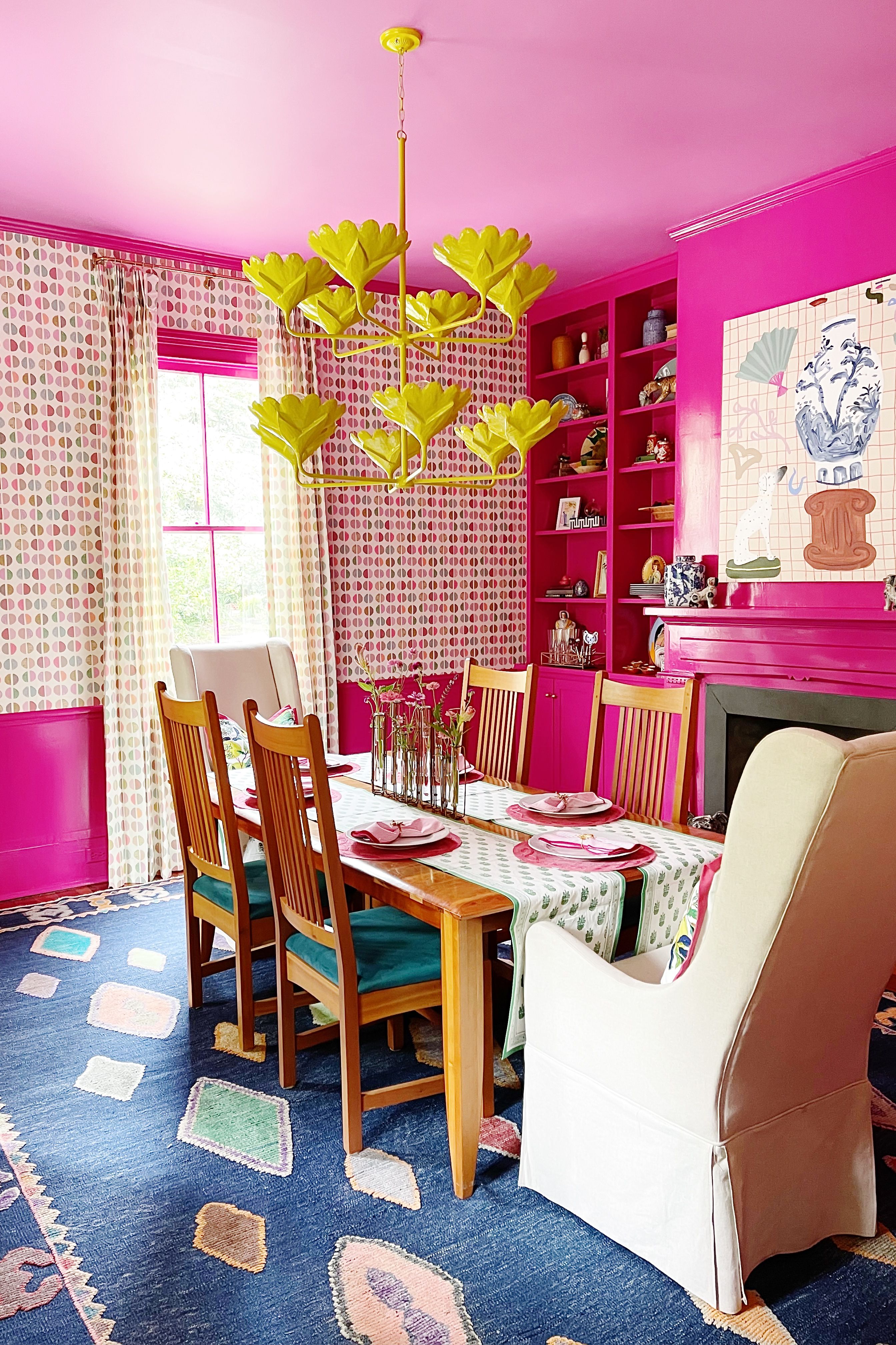 Hot pink dining room featuring a berber-style rug, wooden furniture, and a chartreuse floral chandelier.