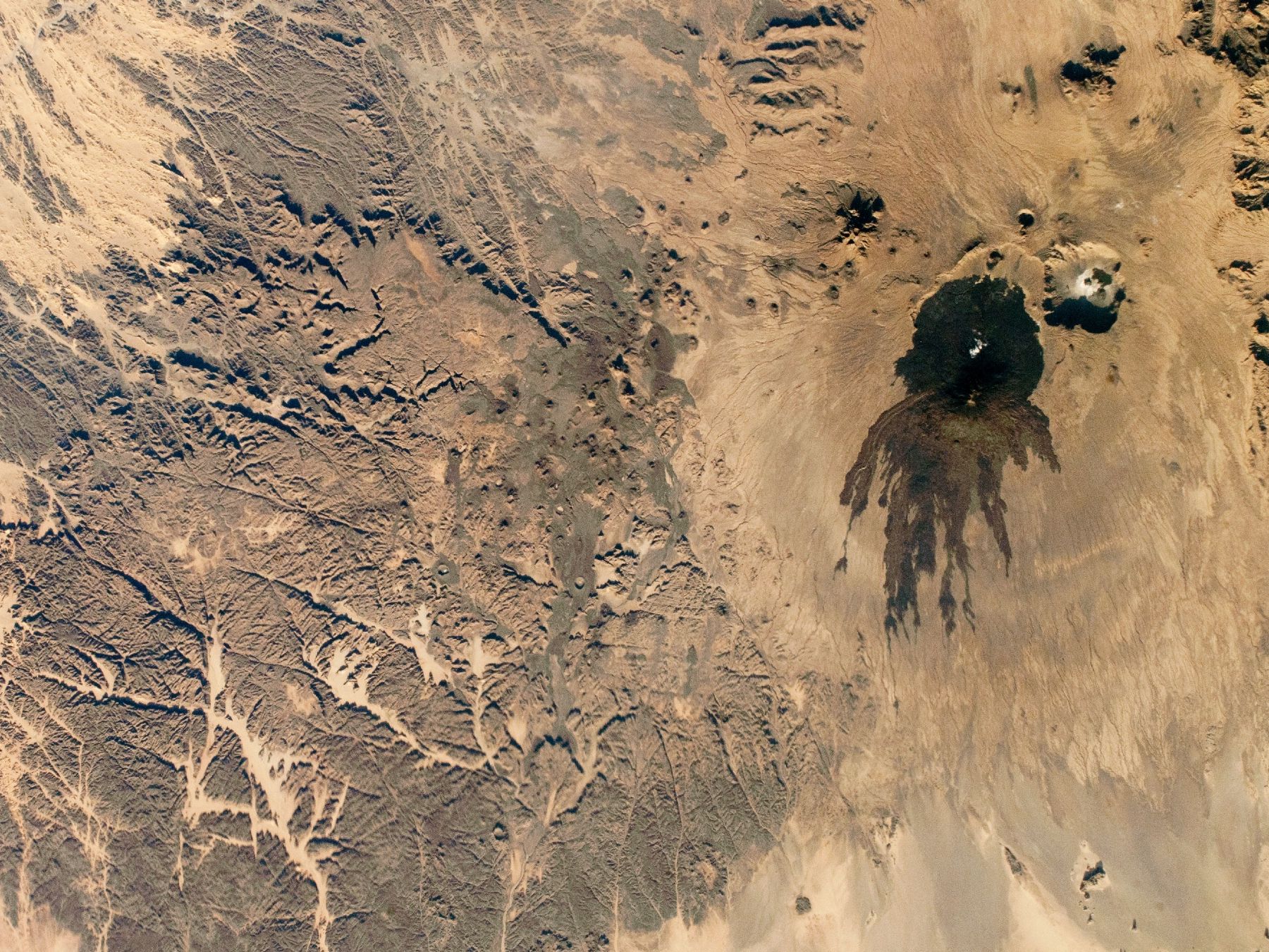 Shadowy tendrils of ancient lava have scarred a dark volcano next