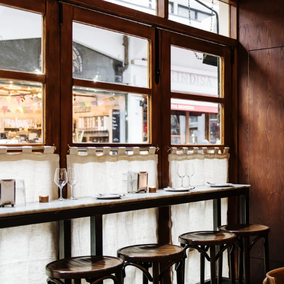 an image of the gorgeous interior of Camille, showing the view onto the market from a high bench table and four wooden stools