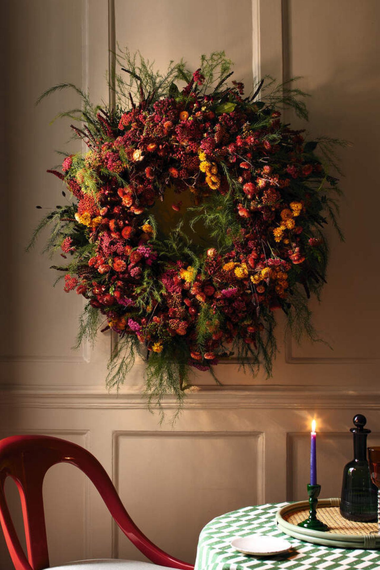 a large, colorful wreath hanging on the wall in front of a table and a chair