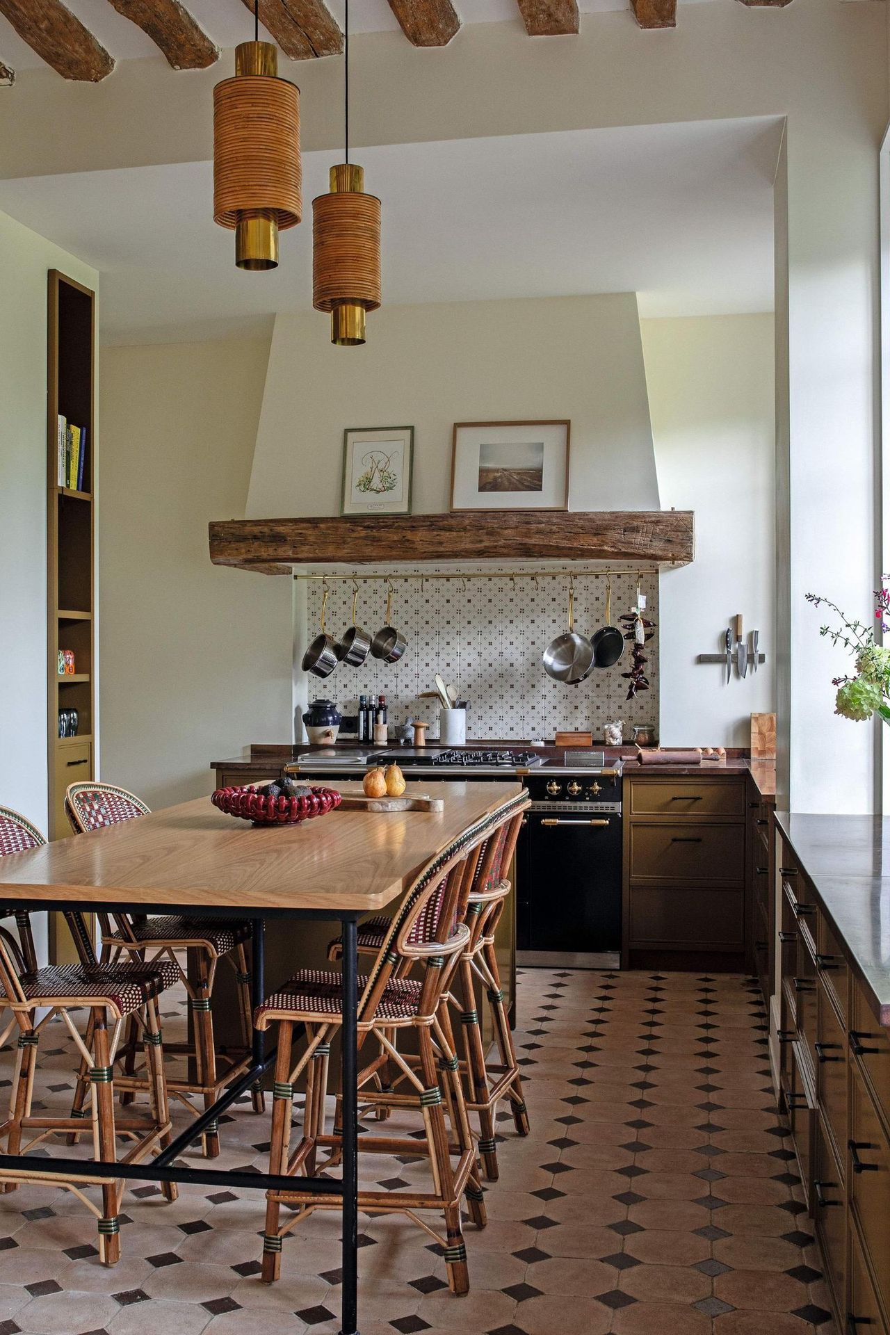 a french rustic kitchen with green ochre cabinetry, ceiling beams and stone floors