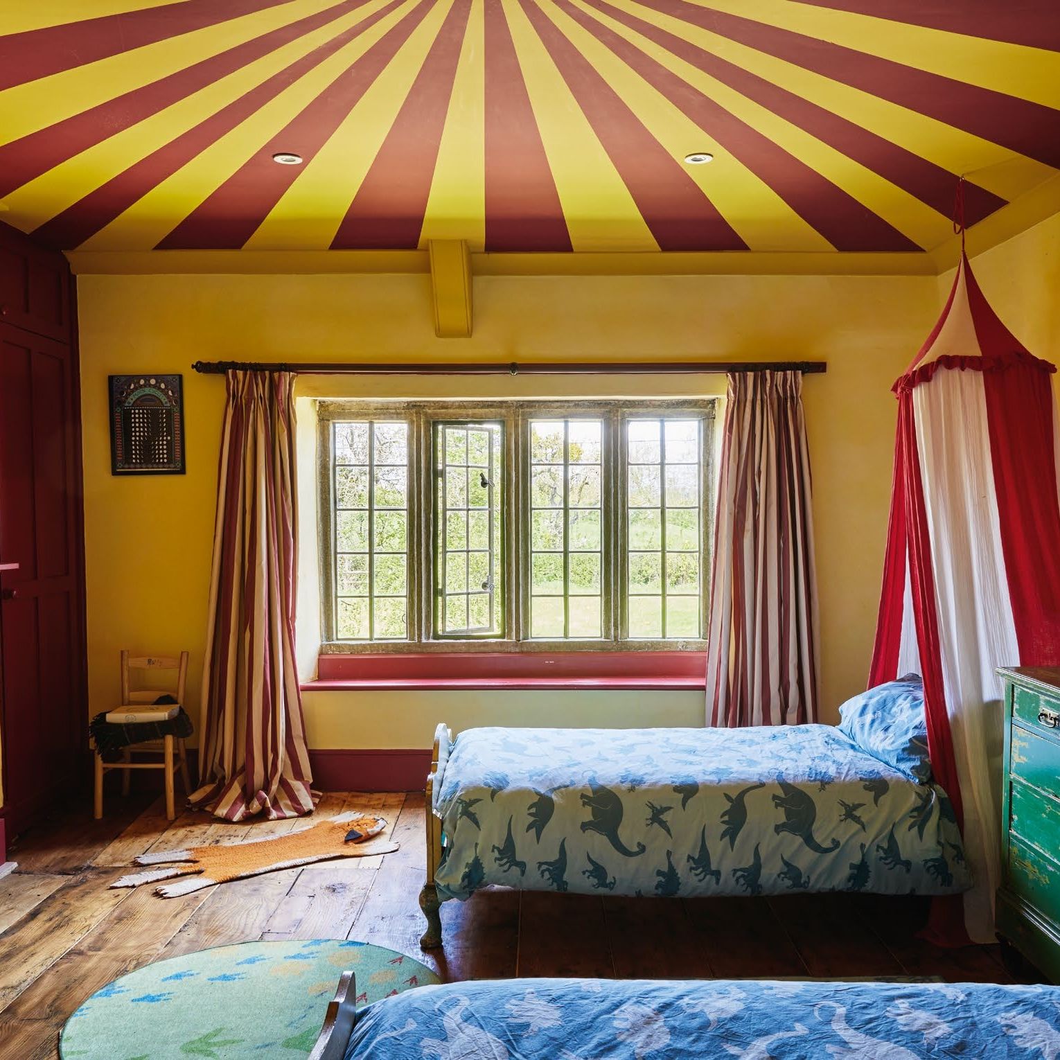 Circus themed children's room in old house with yellow and red striped ceiling and bed canopy