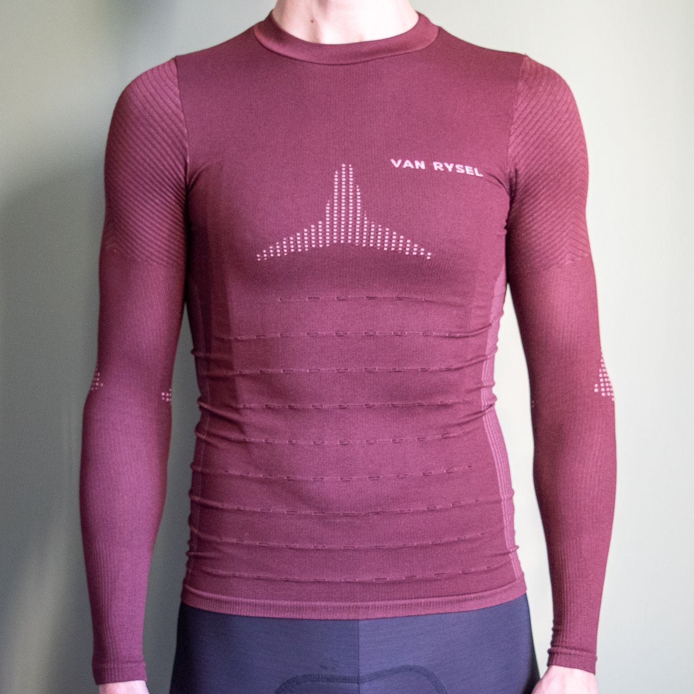 A man wearing a burgundy Van Rysel racing base layer