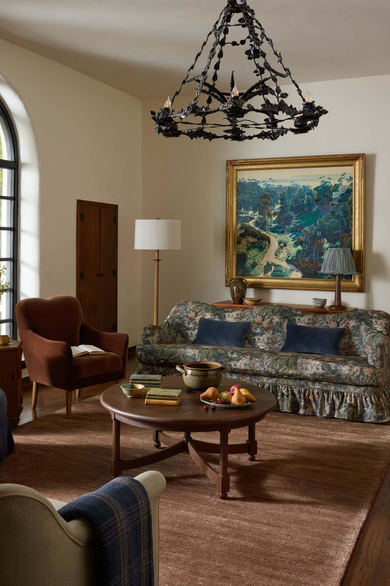 a vintage-inspired living room with a brown rug, a floral couch, and a decorative chandelier
