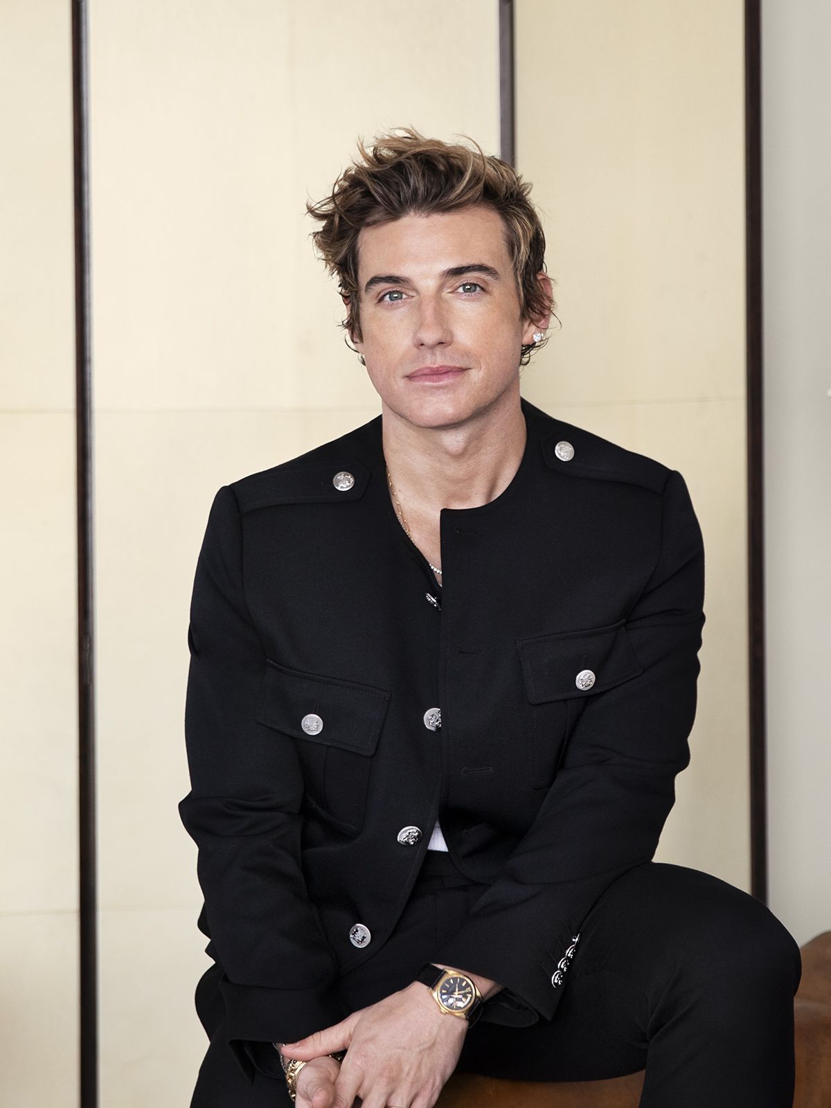 Jeremiah Brent sat on a leather chair in a white room wearing a black jacket