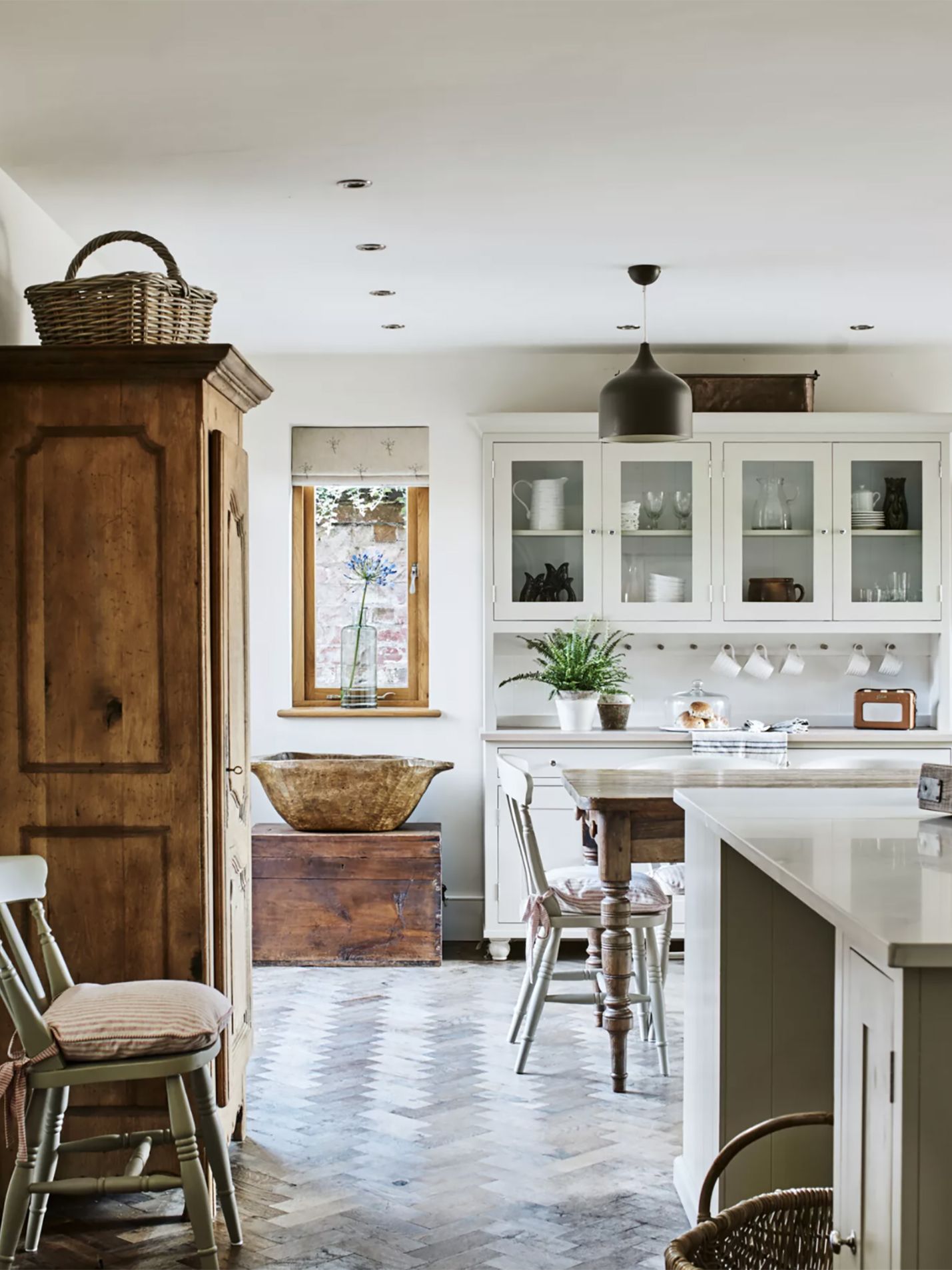 white kitchen with antique wooden dresser and warm parquet wood flooring