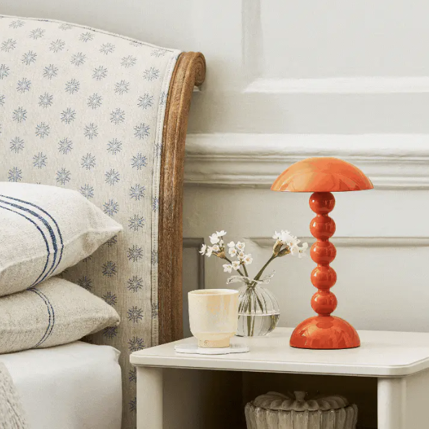 An orange bobbin lamp on a bedside table