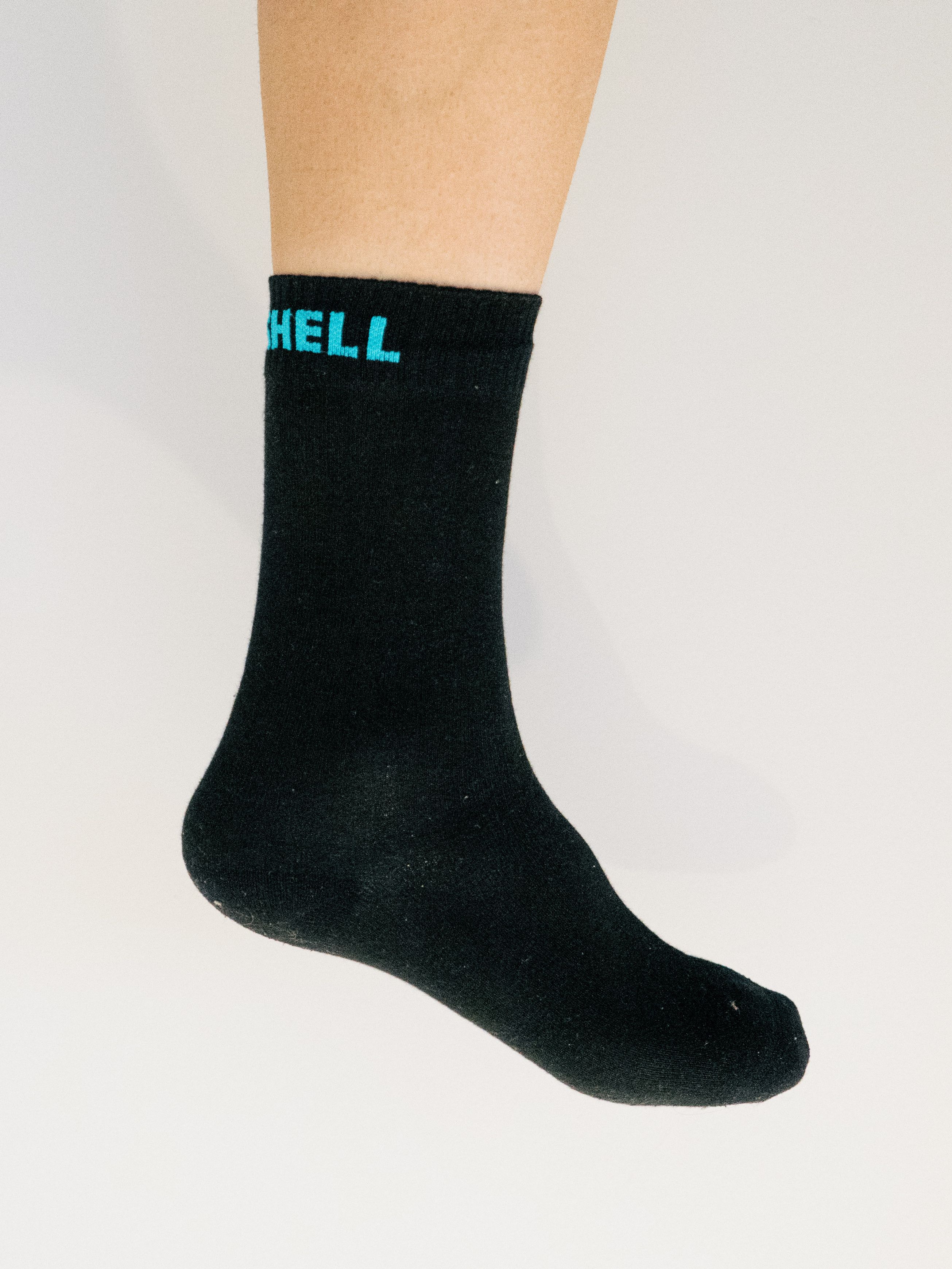 A white leg wears a black cycling sock against a white background