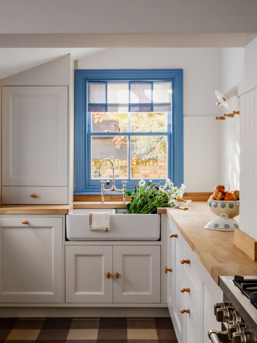 Country-style kitchen with blue-framed window and checked decorative blind
