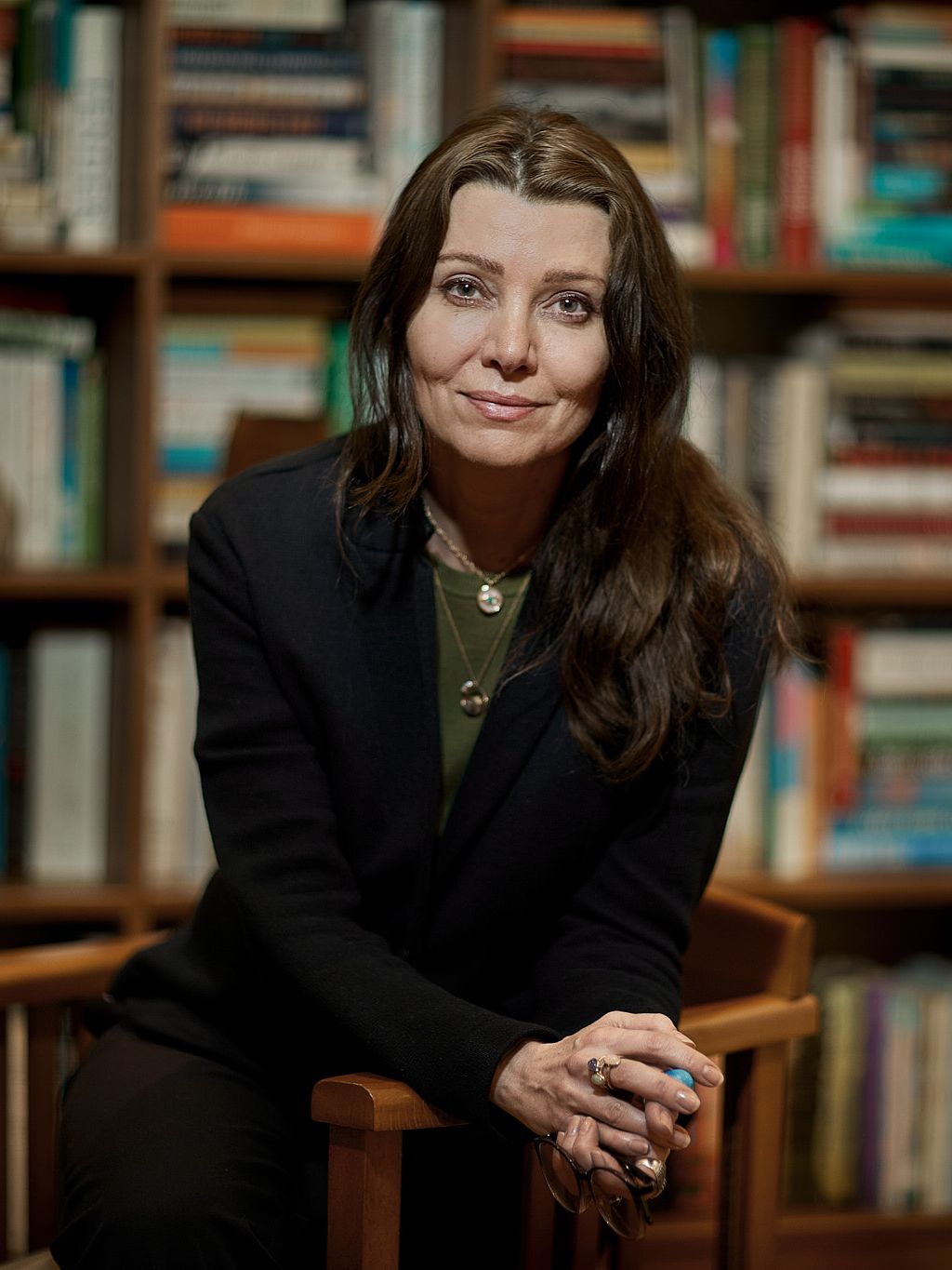A woman sitting on a chair smiling at the camera in a library