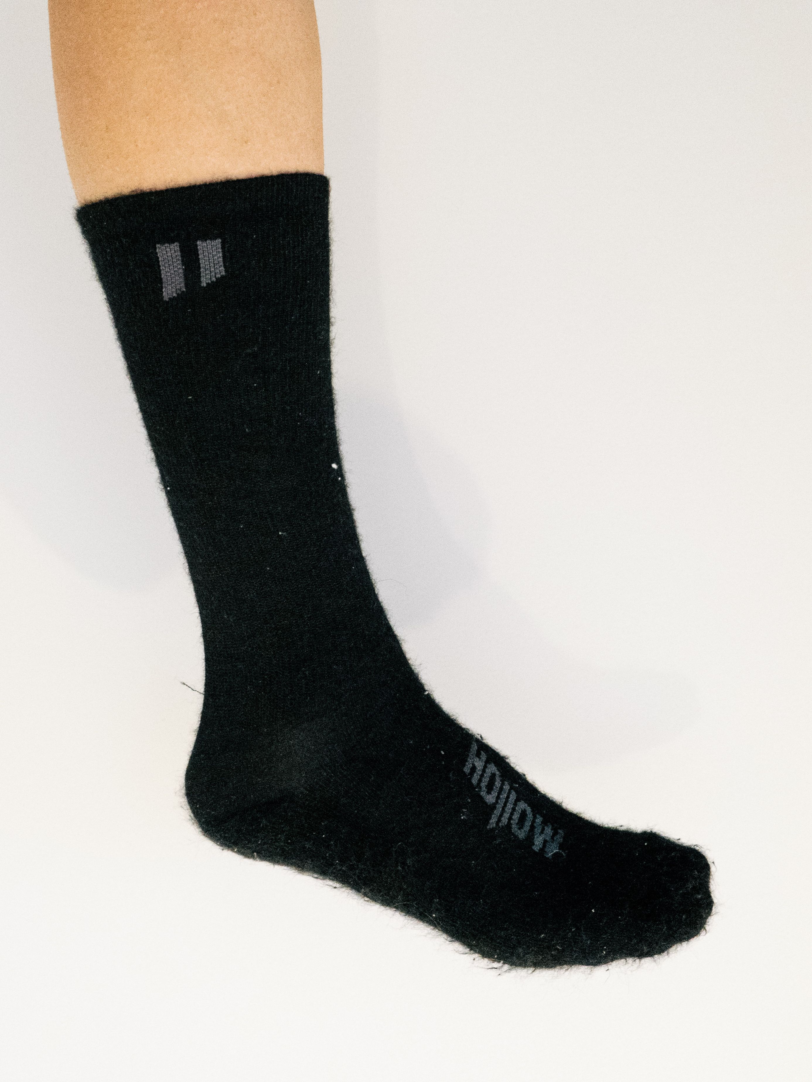 A white leg wears a black cycling sock against a white background
