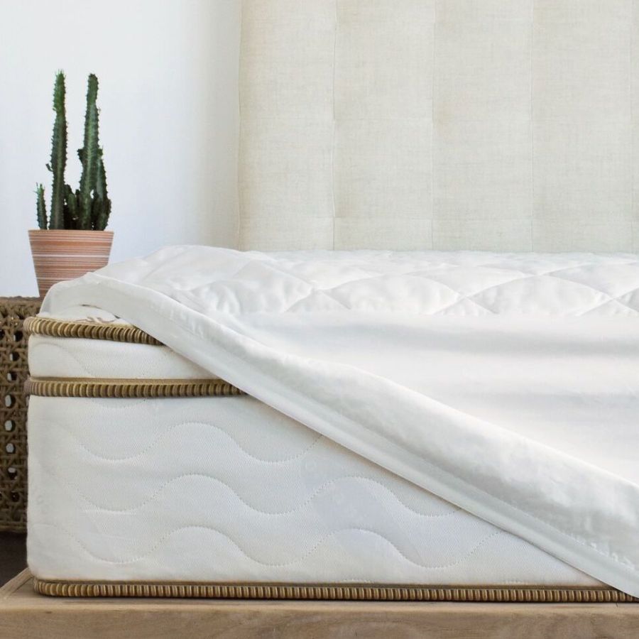 Saatva Waterproof Mattress Protector on a bed against a white wall. 