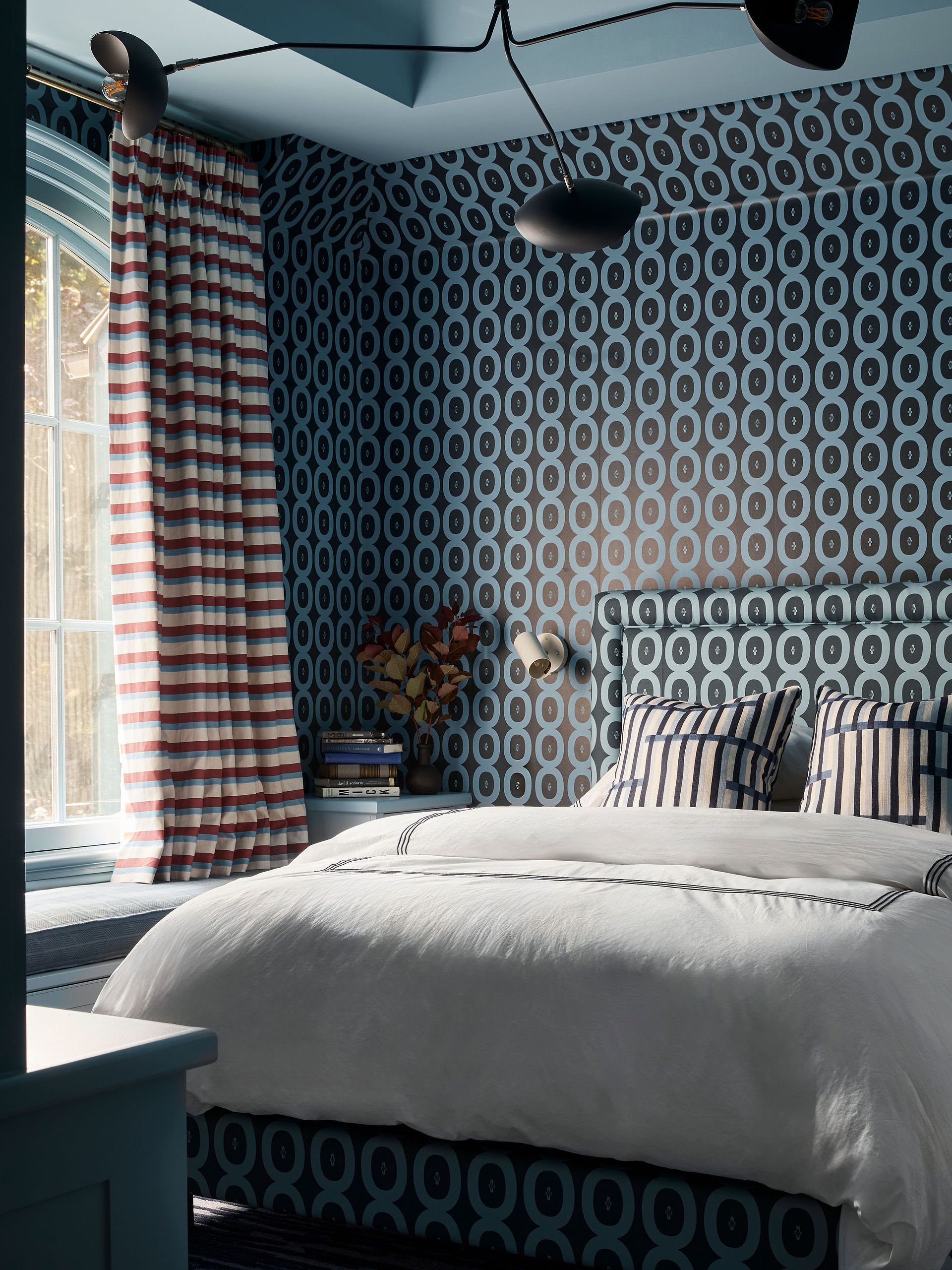 A teenage son's bedroom with a graphic blue pattern of circular motifs across the walls, and also covering the headboard.