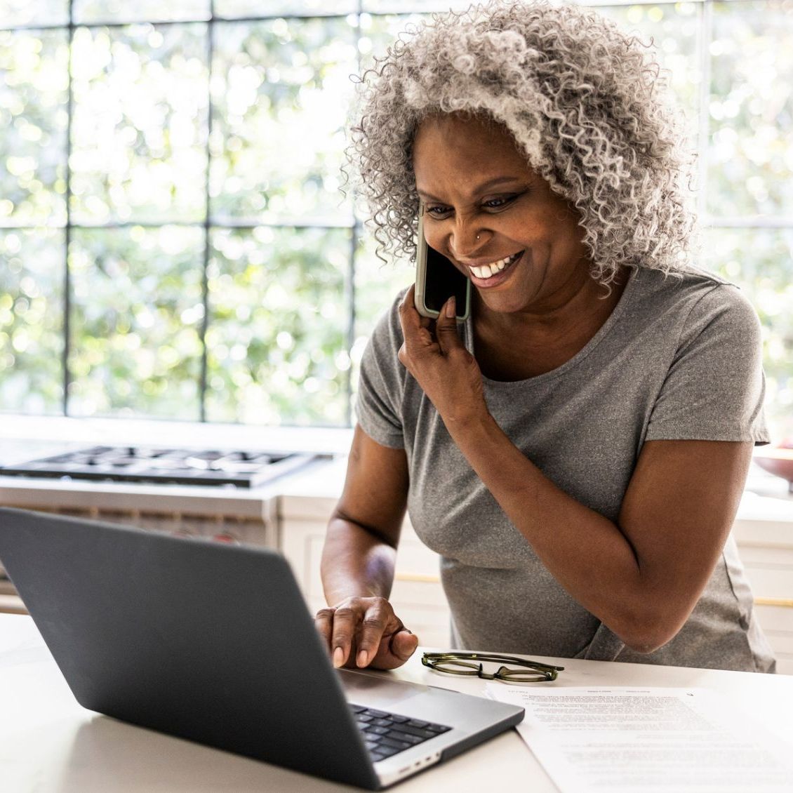 A woman talking on the phone while looking at her laptop