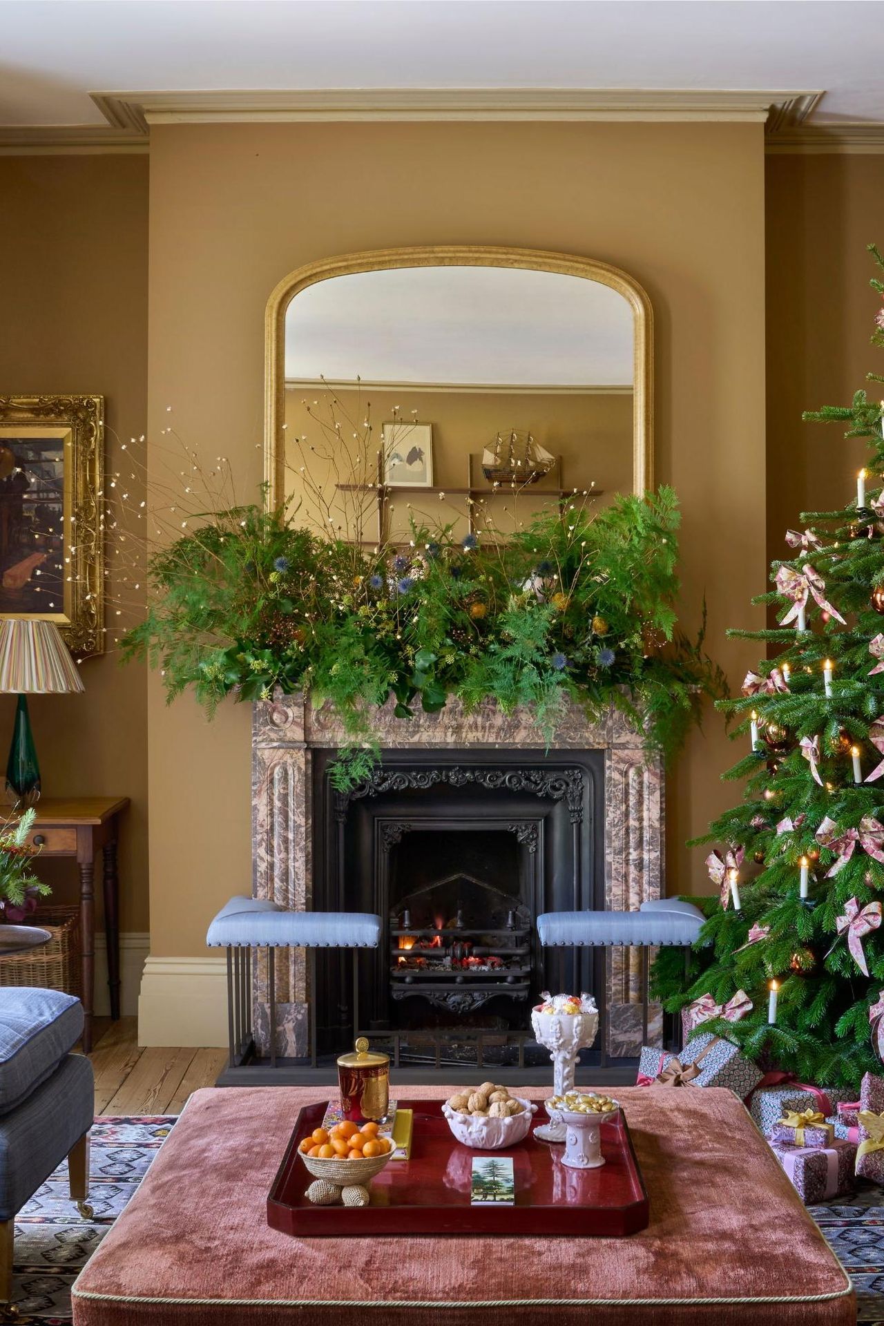 Yellow living room decorated for Christmas with a tree decorated with bows in one corner and blue seating